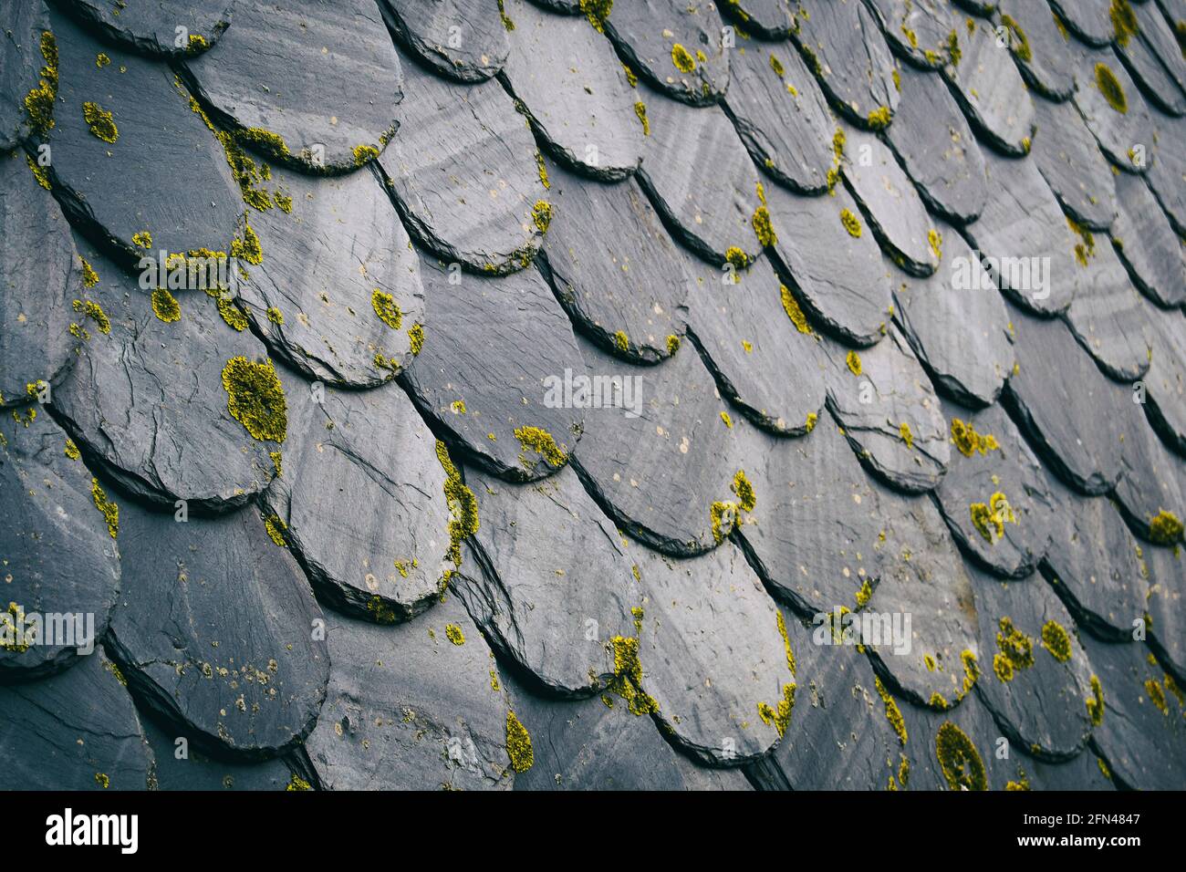 roof with old dark colored tiles, between black and gray. Create a textured pattern from an angled perspective Stock Photo