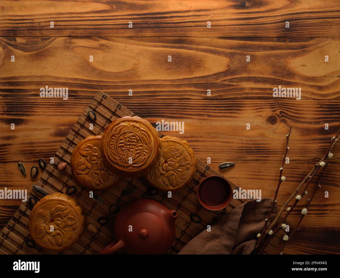 Top view of traditional moon cakes on bamboo mat with tea set and copy space on rustic table. Chinese character on the moon cake represent "five kerne Stock Photo