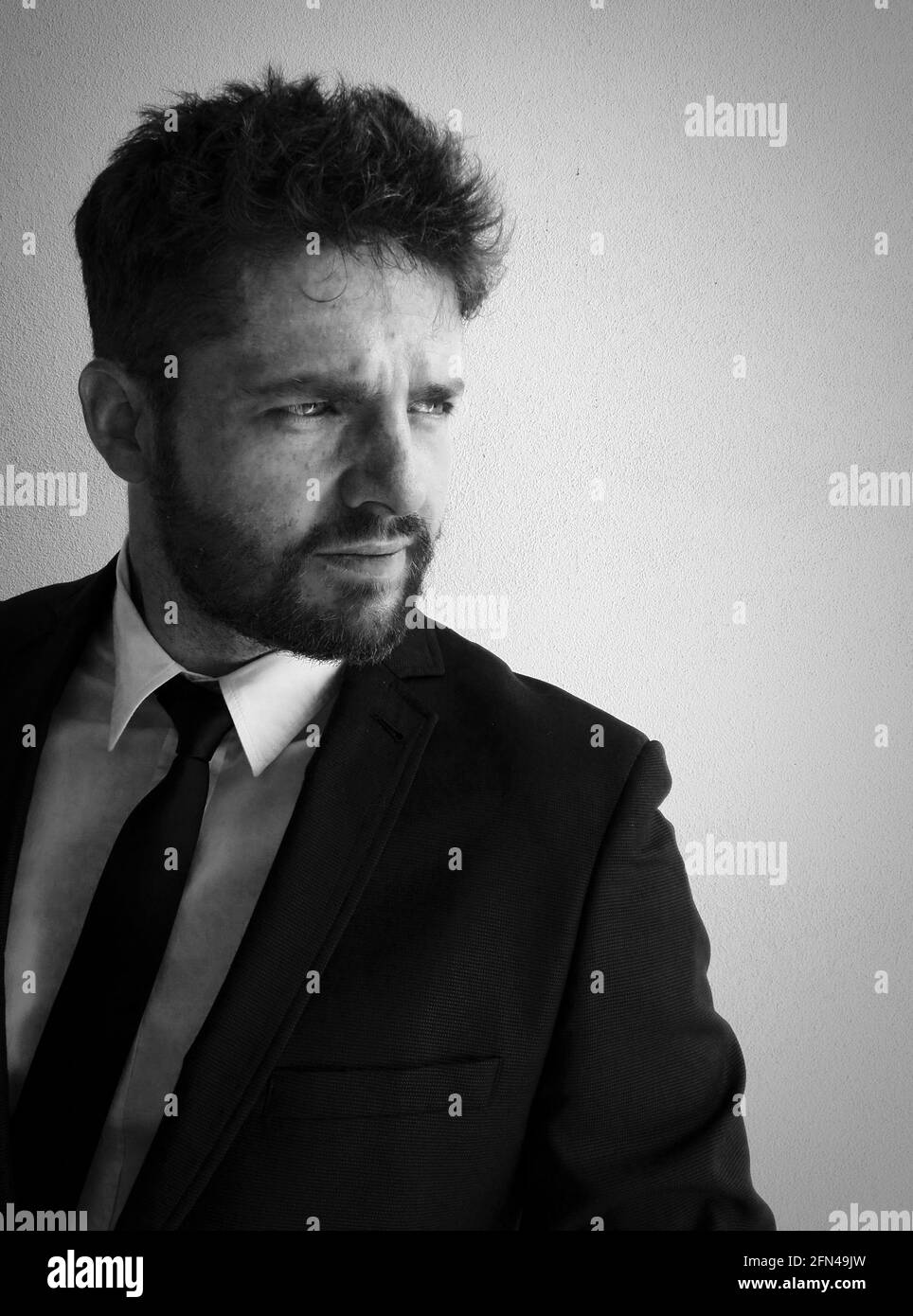 Black and white portrait of elegant man with beard. Man with clear eyes and gloomy look in a suit and tie. Stock Photo