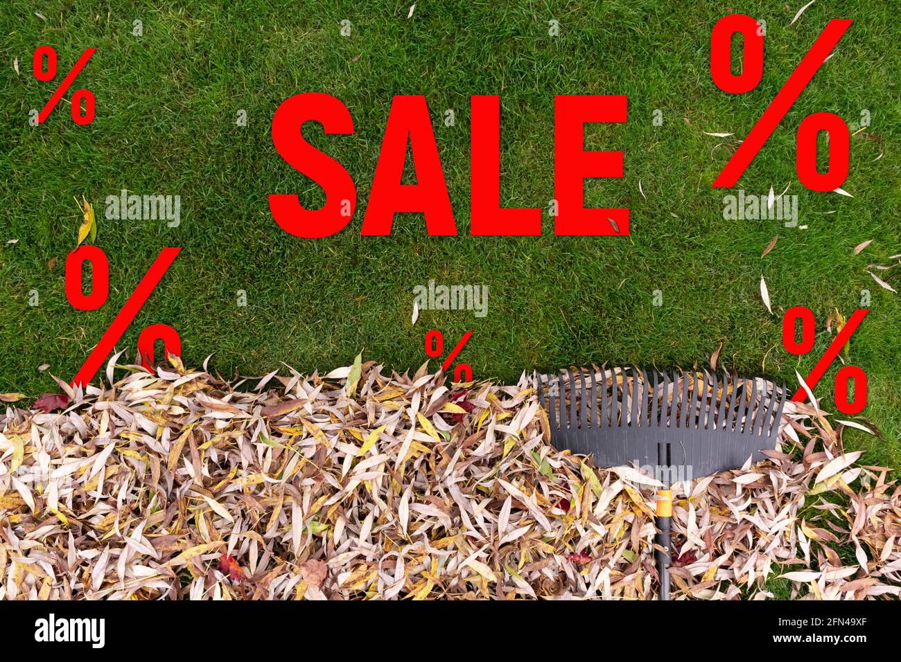 Pile of fall leaves with rake on lawn. Autumn sale Stock Photo