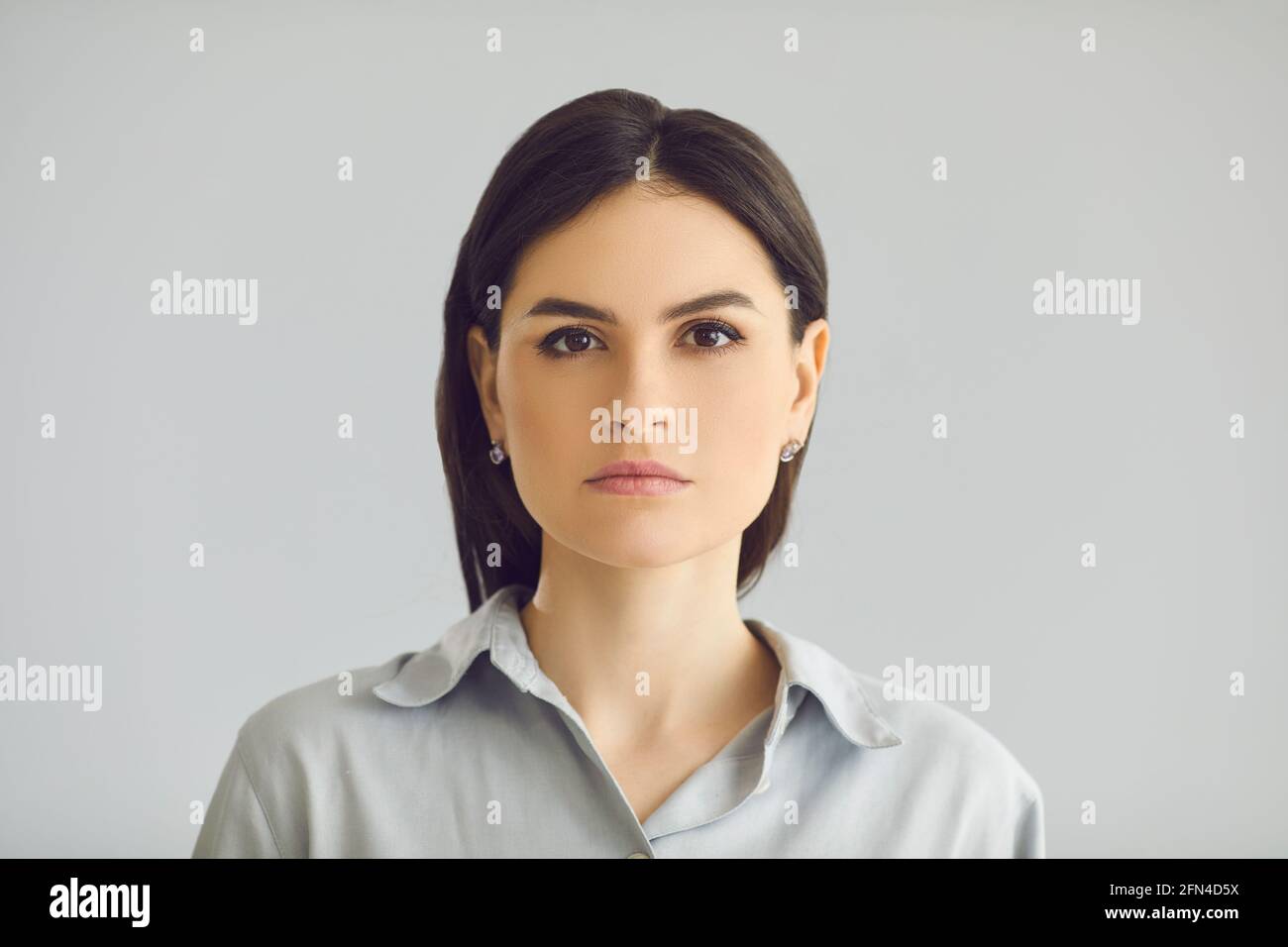 Young thoughtful serious caucasian woman face portrait on studio grey background Stock Photo