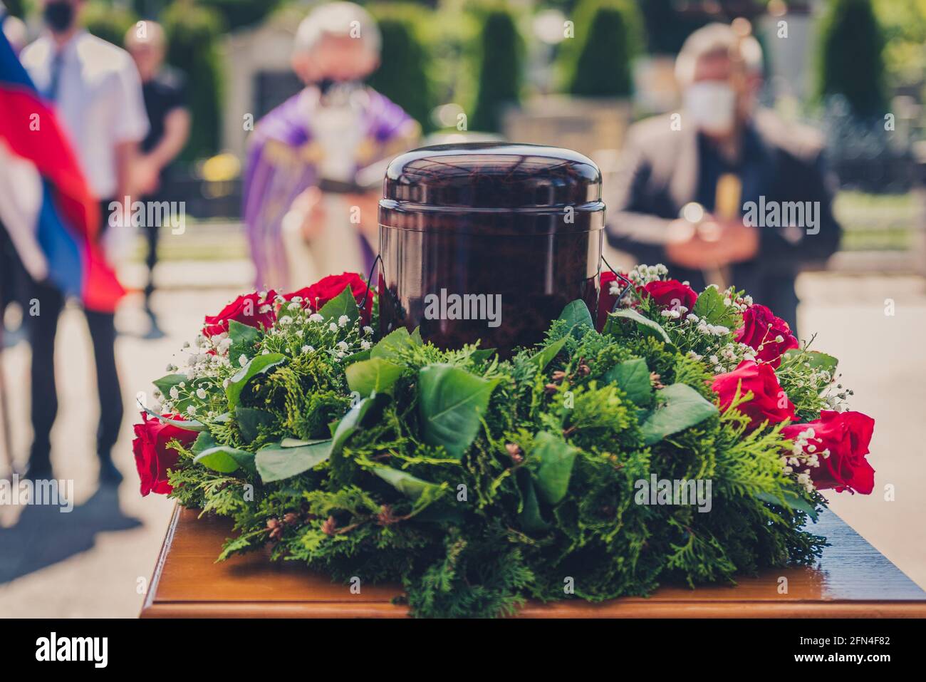 Funerary urn with ashes of dead and flowers at funeral. Burial urn