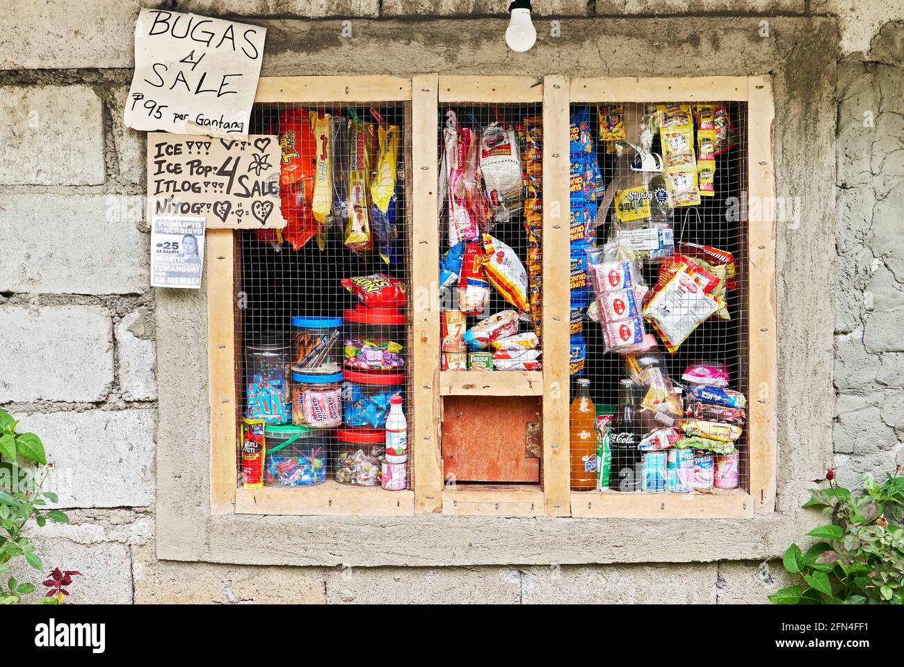 Grilled window functioning as a neighborhood sari-sari store in the Philippines. Sold are snacks, soft drinks, candies and groceries at a cheap price Stock Photo