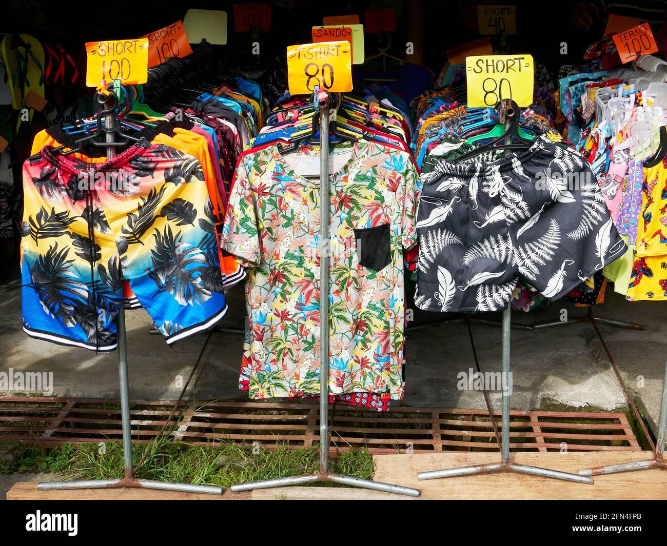 Several display stands with hangers full of colorful clothes for sale in a stall in the Philippines, a common sight during the covid pandemic times Stock Photo