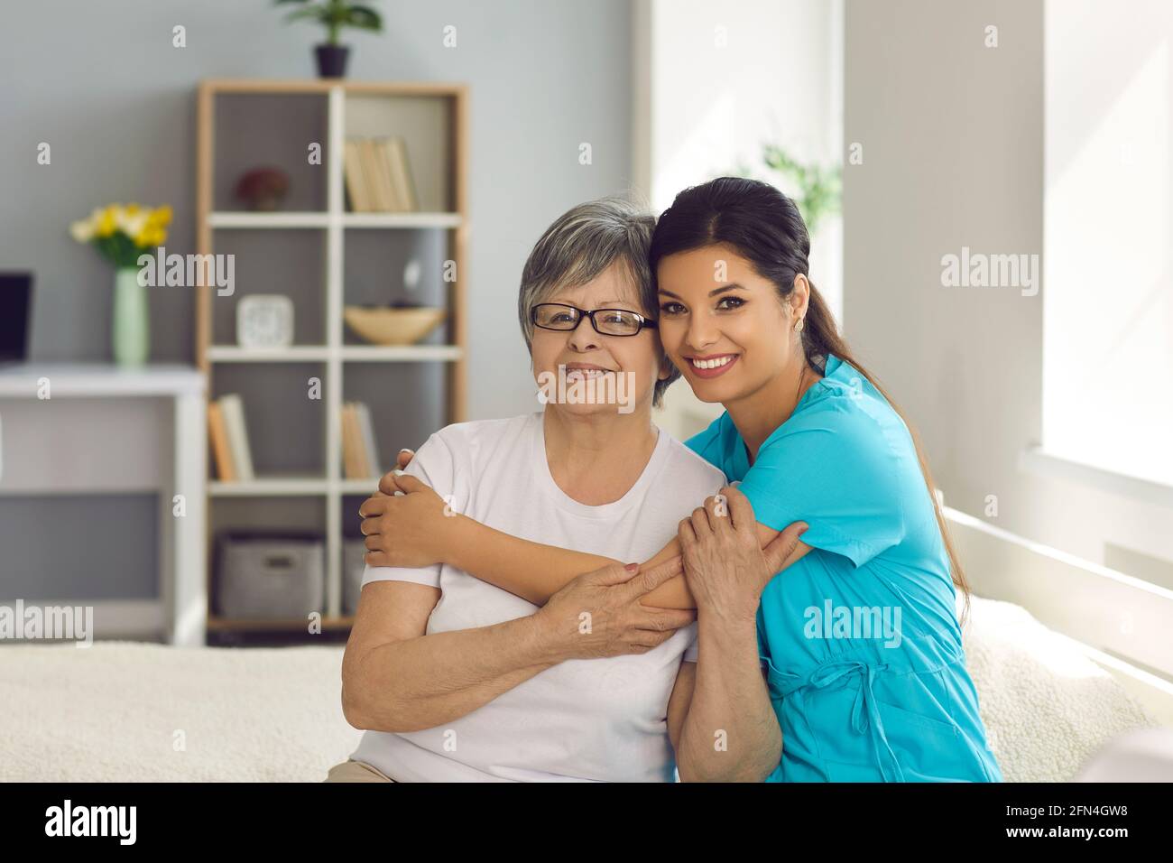 Happy senior woman together with her home care nurse or caregiver smiling at camera Stock Photo
