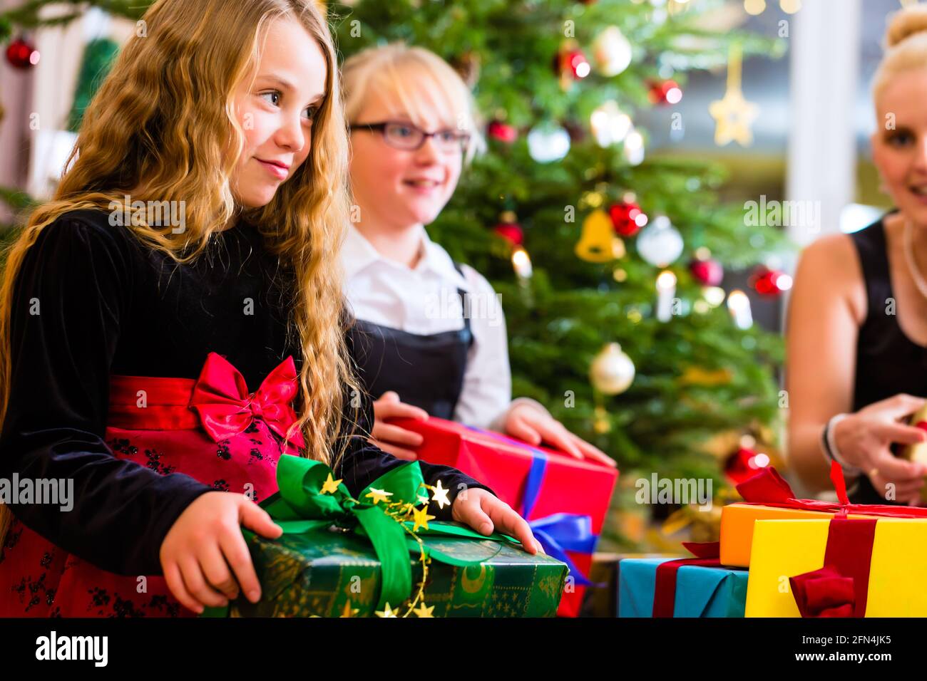 Mother and children with presents on Christmas day in front of Xmas tree Stock Photo