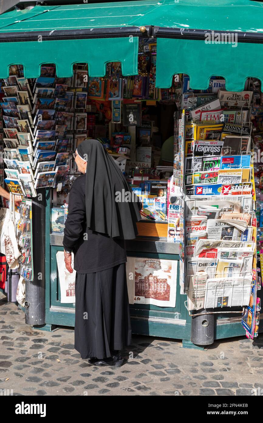 A nun stands at an old fashioned news kiosk in Piazza Santa Maria in Trastevere, Rome, Italy. Stock Photo