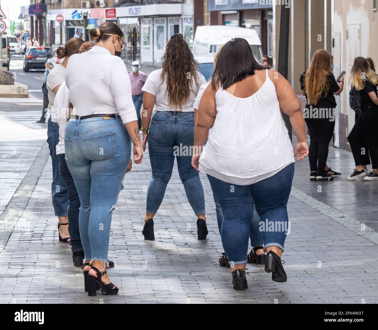 Rear view of fuller figure female models during street photo shoot in Spain Stock Photo