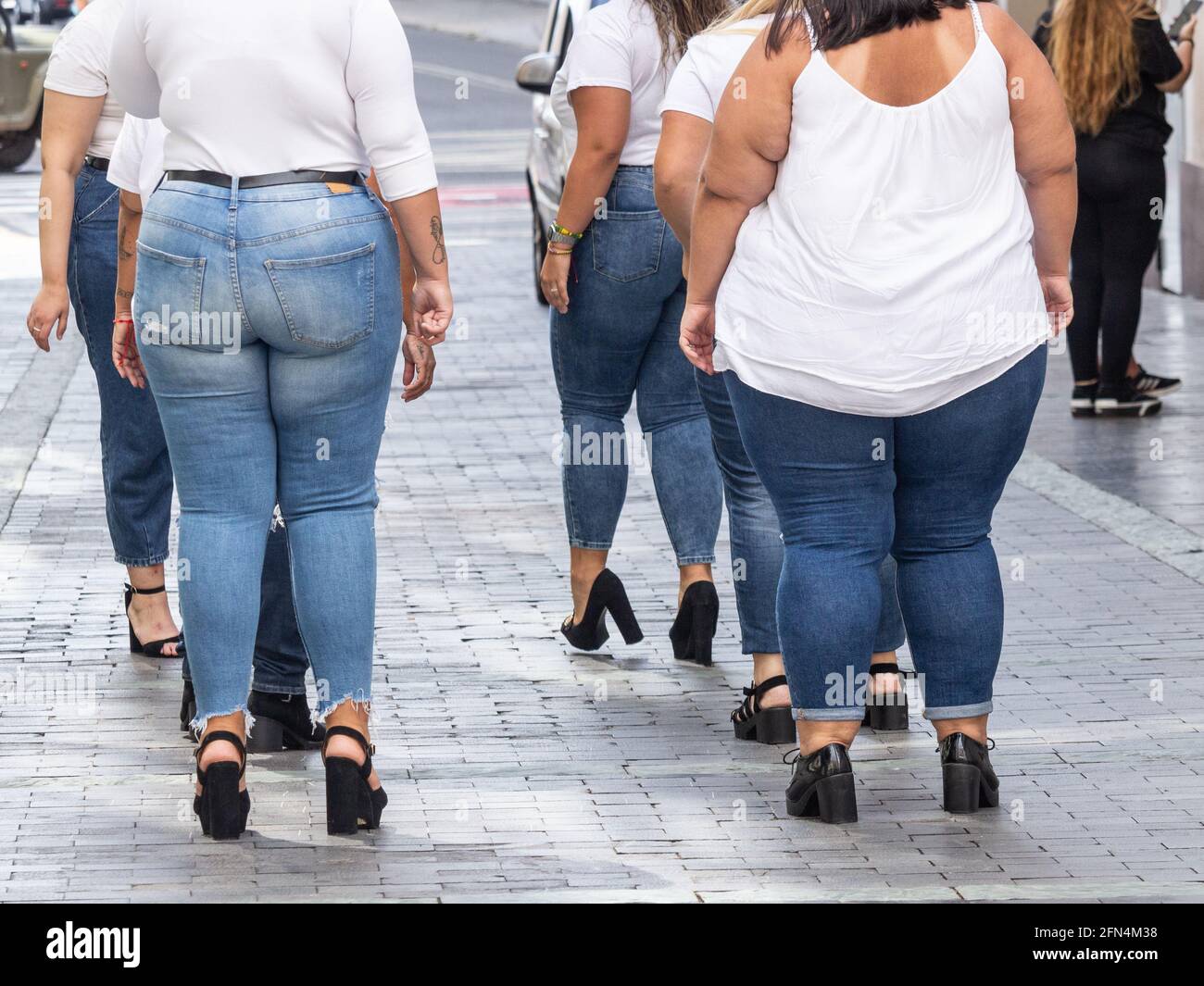 Rear view of fuller figure female models during street photo shoot in Spain Stock Photo