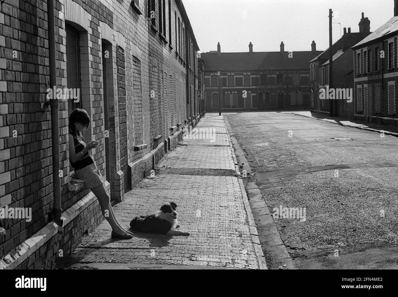 A girl and her dog outside her house in a street where most of the houses are bricked up awaiting demolition, Splott, Cardiff, 1975 Stock Photo
