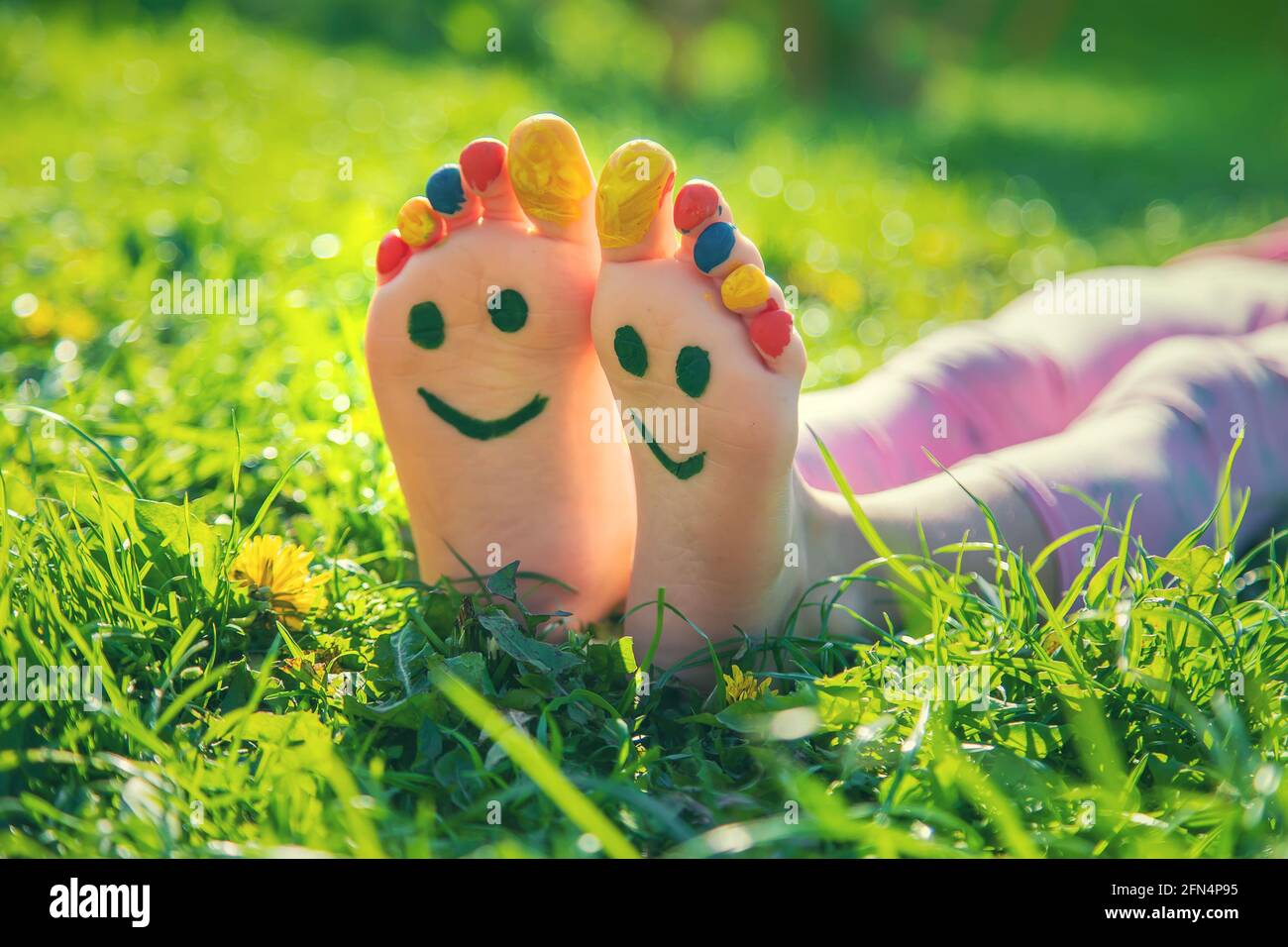 Child feet on the grass drawing a smile. Selective focus. Kid Stock Photo -  Alamy