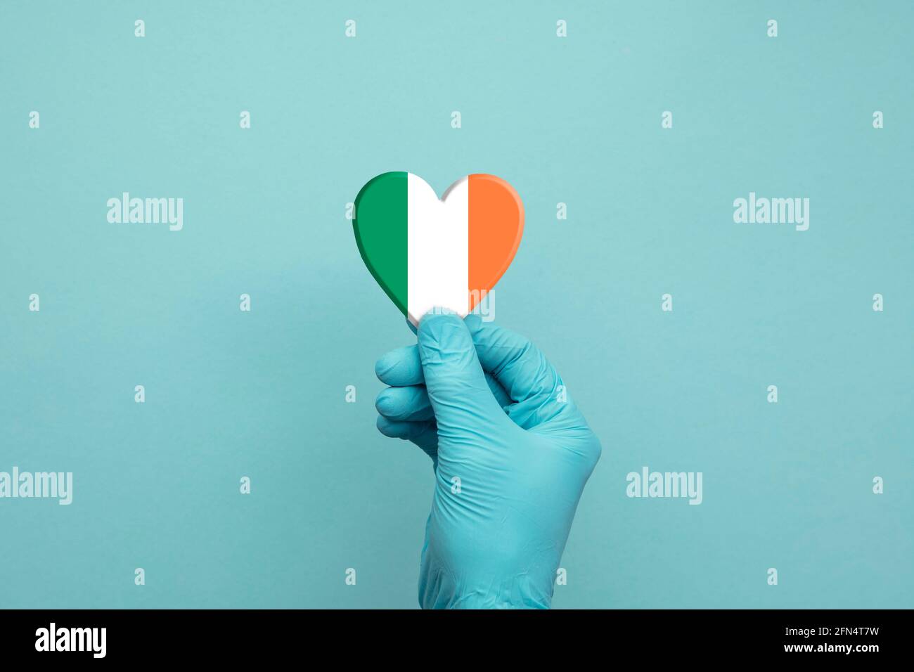 Hands wearing protective surgical gloves holding Ireland flag heart Stock Photo