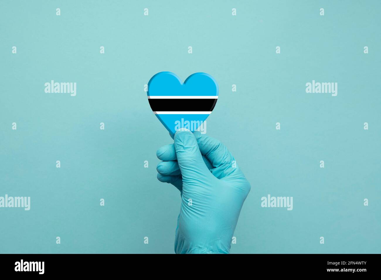 Hands wearing protective surgical gloves holding Botswana flag heart Stock Photo