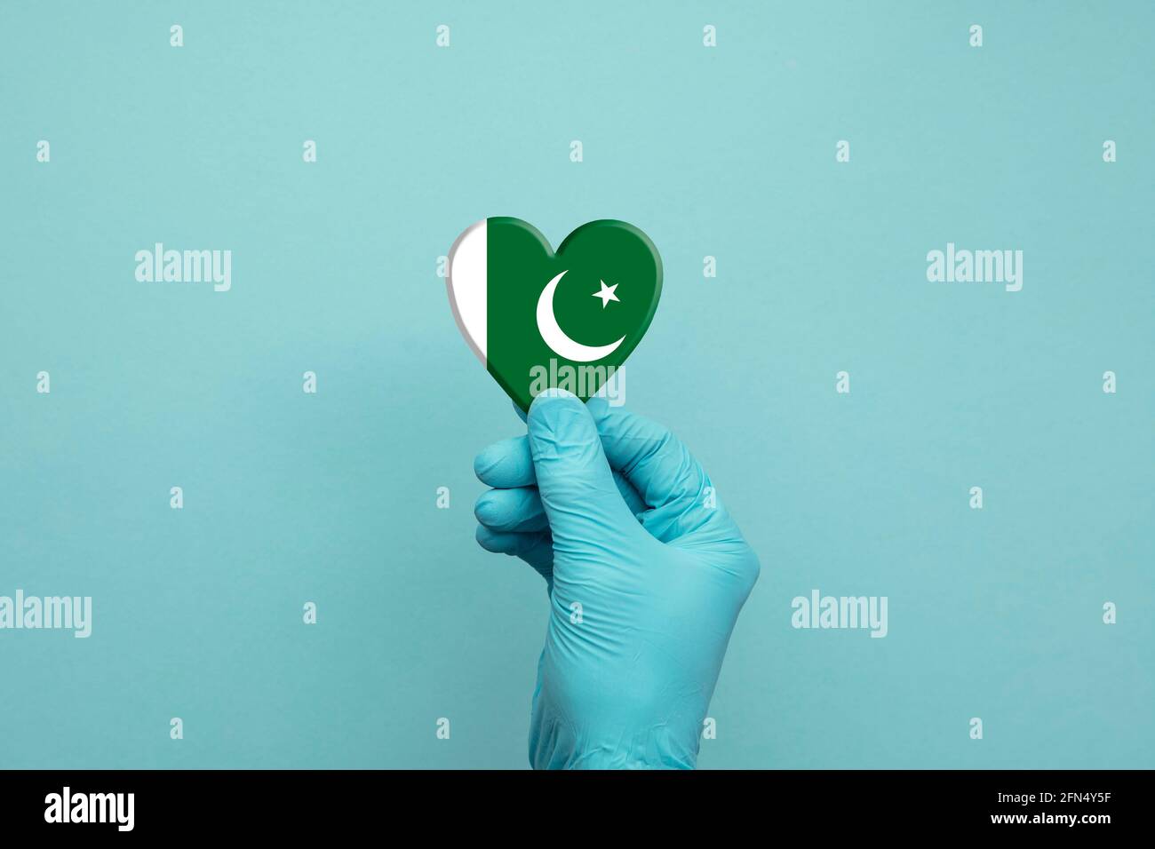 Hands wearing protective surgical gloves holding Pakistan flag heart