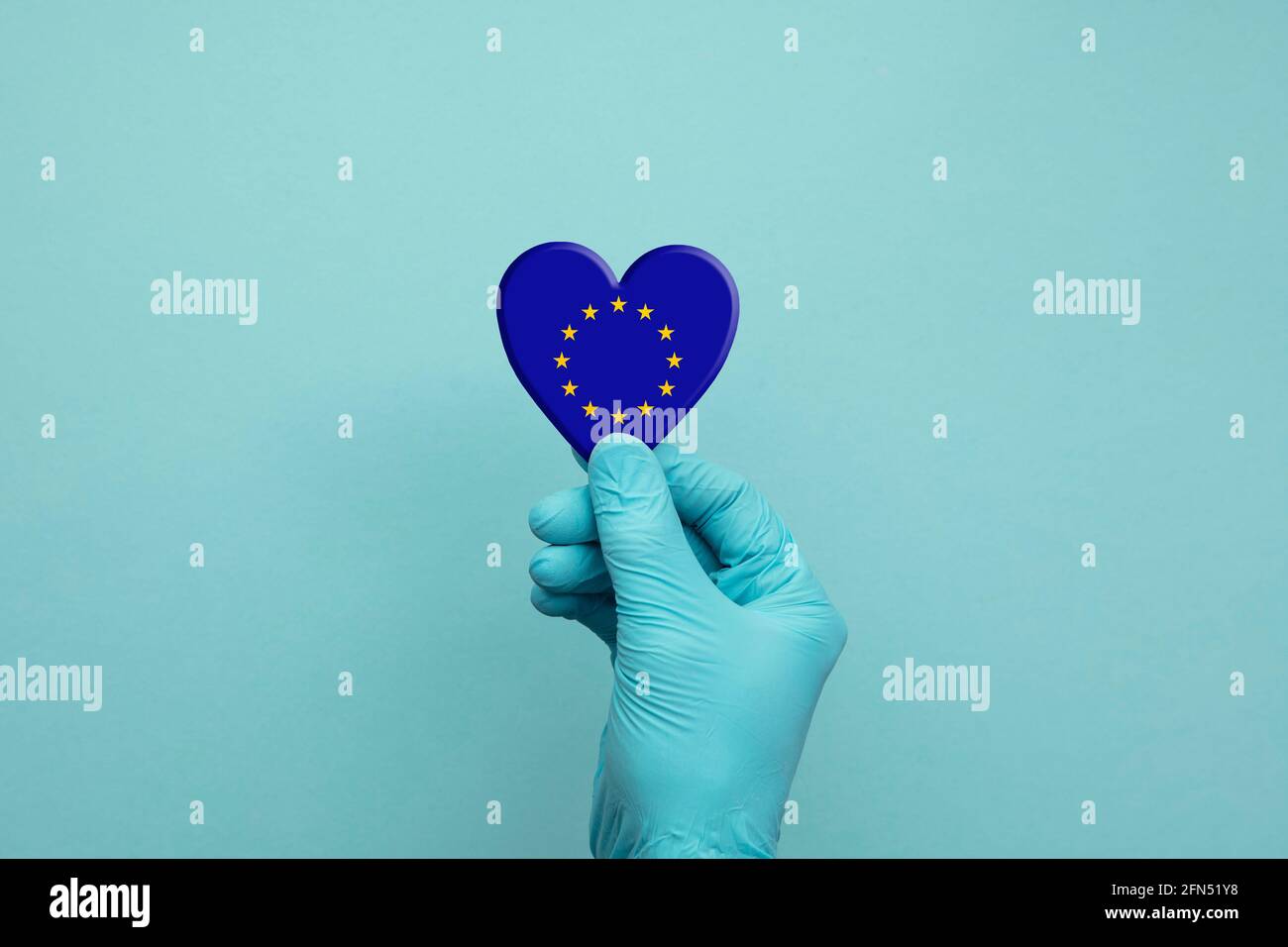 Hands wearing protective surgical gloves holding European Union flag heart Stock Photo