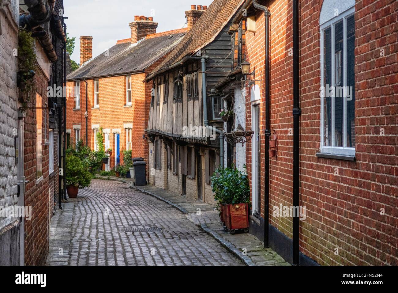 Historic cobbled street in the Cathedral city of Canterbury in Kent, UK. Timber framed buildings mixed with later brick built houses. Stock Photo