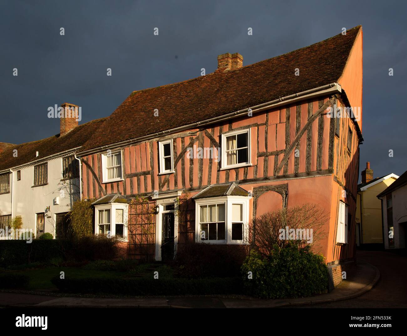 Late afternoon sunlight hits an historic half-timbered house in Lavenham, Suffolk. With storm clouds in the background. Stock Photo