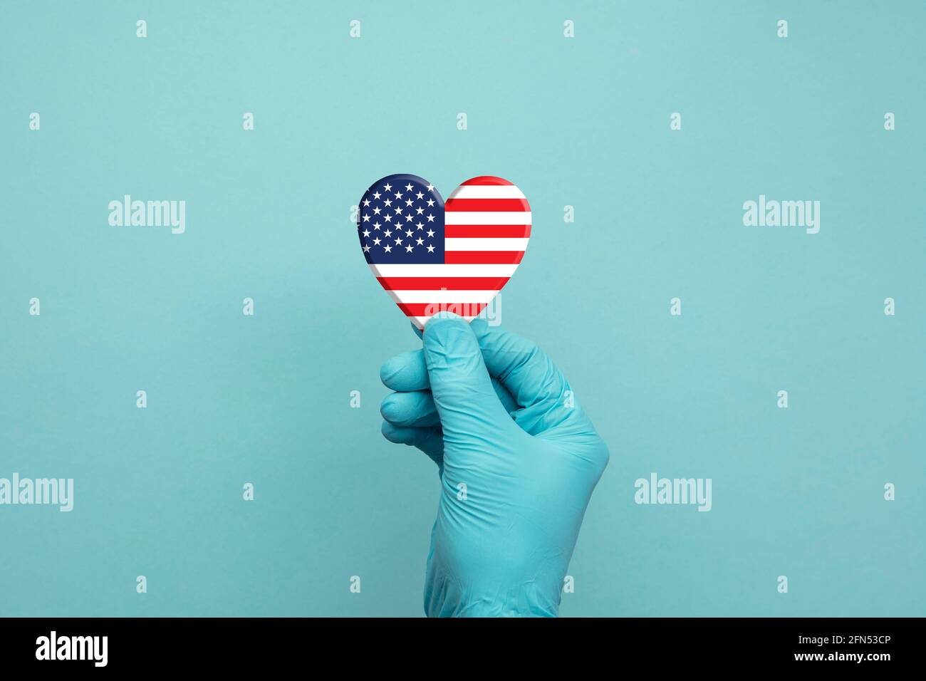 Hands wearing protective surgical gloves holding USA flag heart Stock Photo