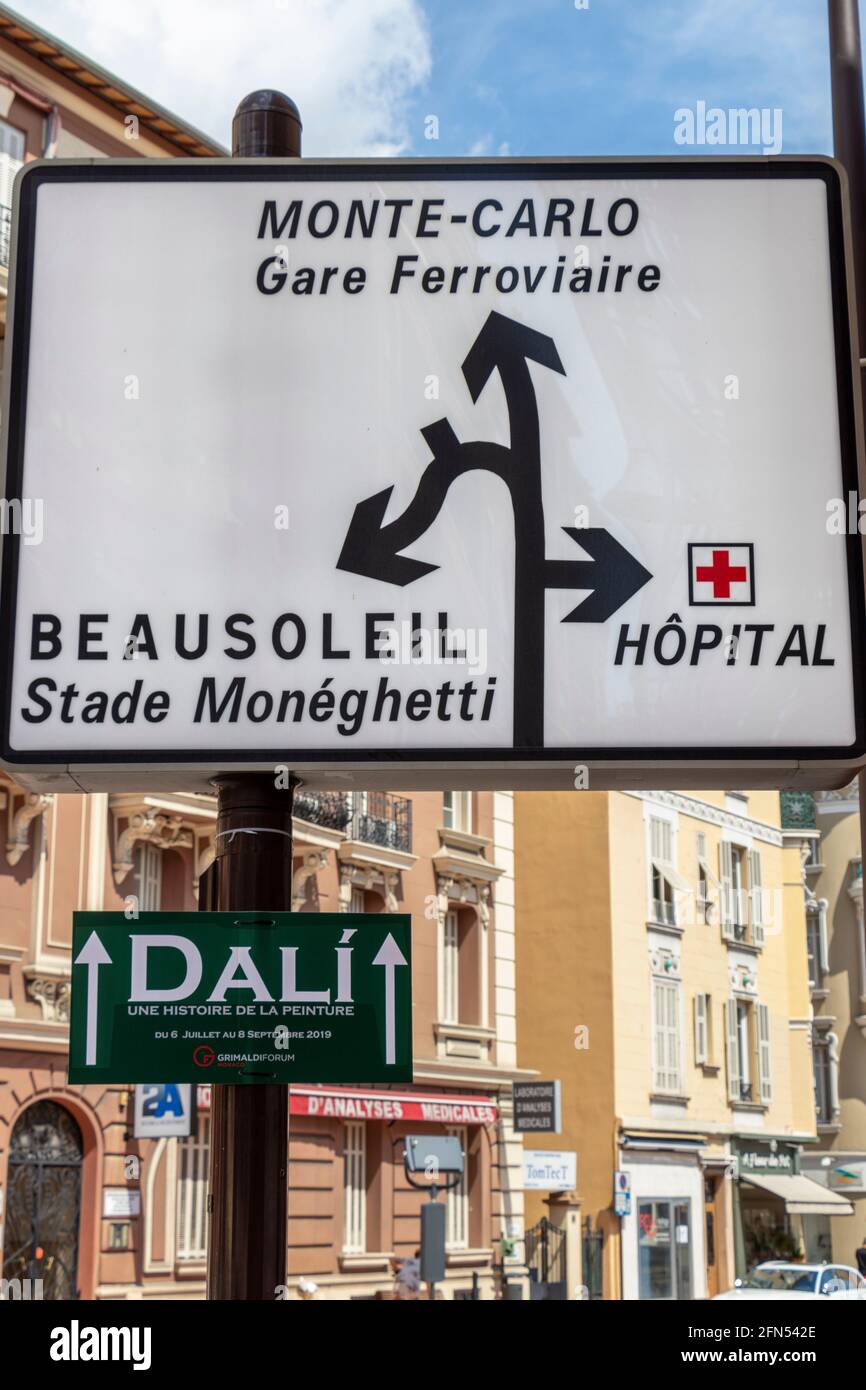 Road sign for Monte Carlo, Beausoleil and the hospitalin Monaco. Dali event notice attached. Stock Photo