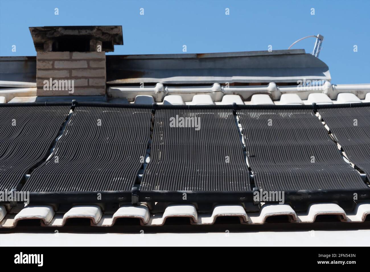 Solar water heating tubes system on the roof of a house. Pool solar heating with black tubes