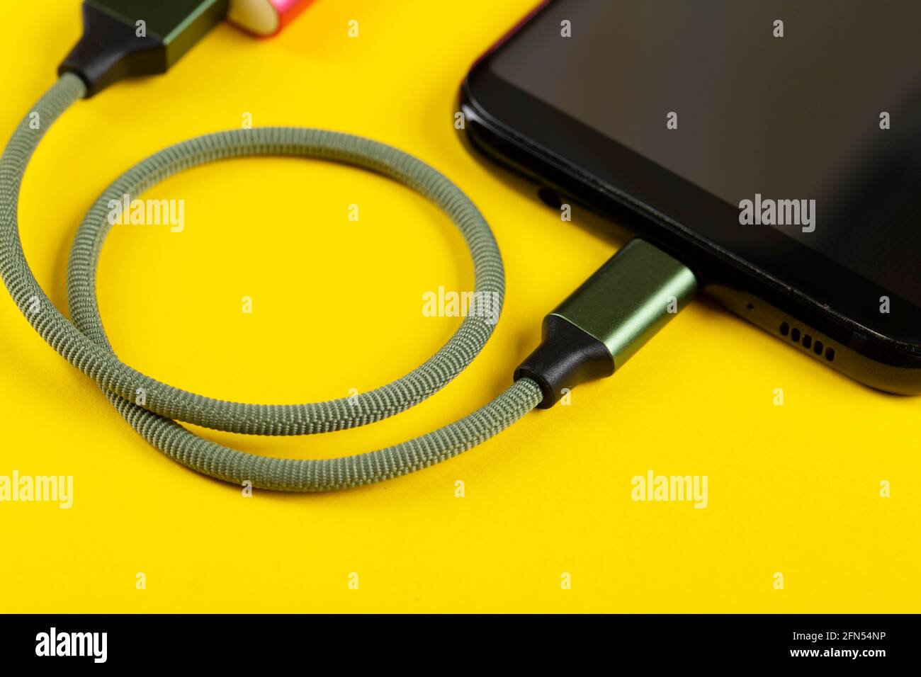 Charging a mobile phone on a yellow background. Stock Photo
