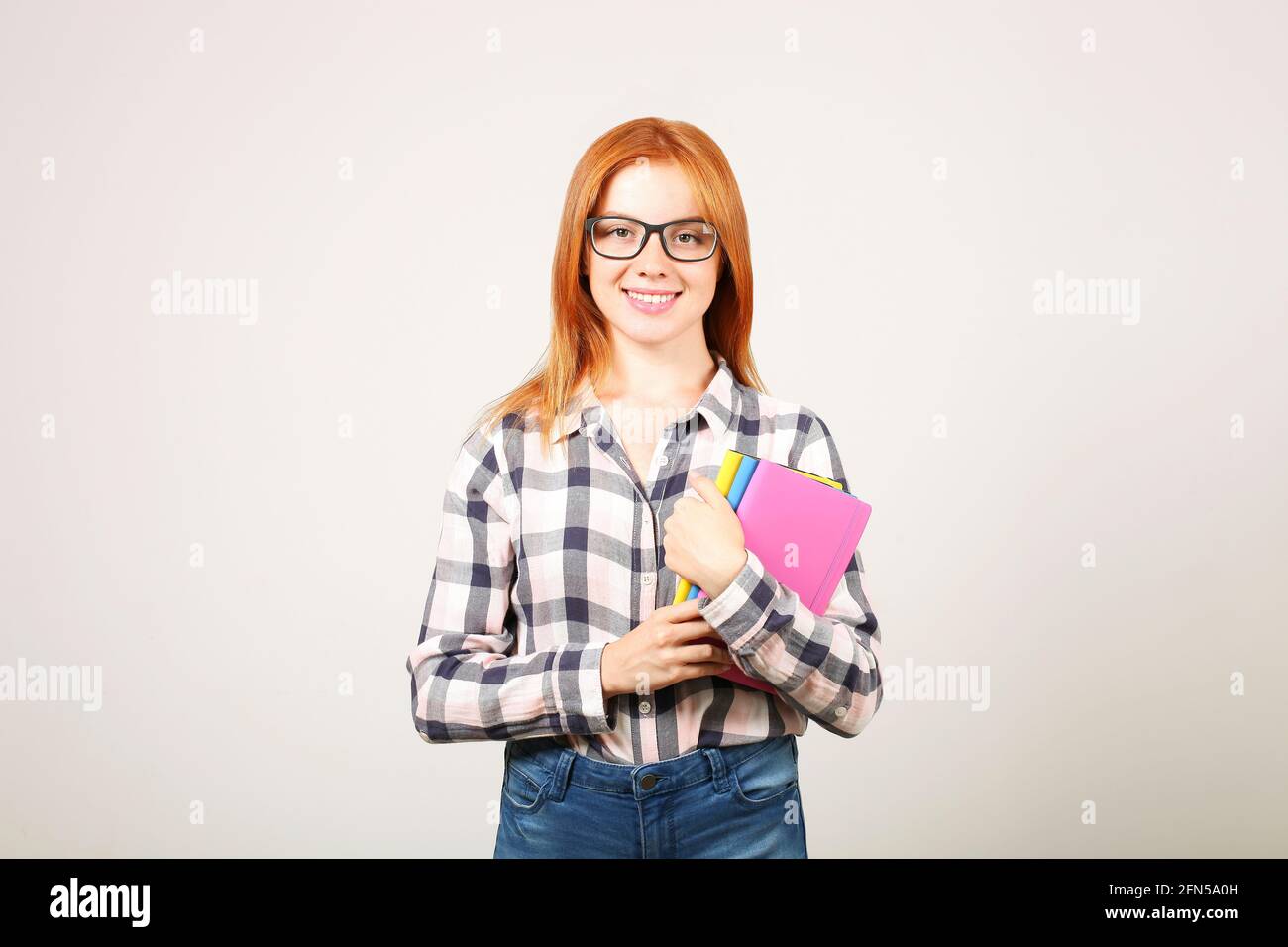 Young beautiful woman with natural red head wearing checkered flannel shirt  and black frame glasses holding bunch of notebooks and smiling. Female stu  Stock Photo - Alamy