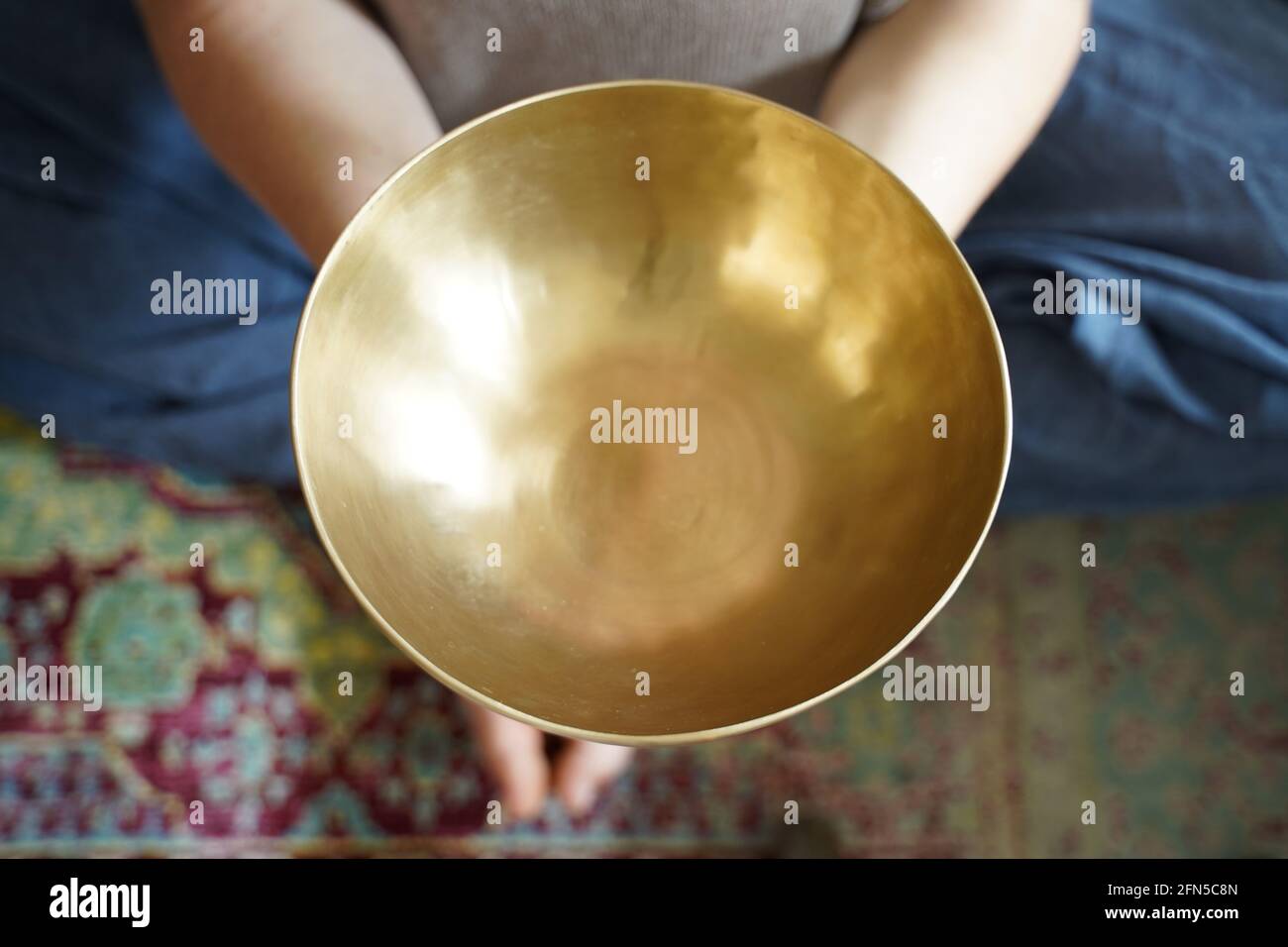 Caucasian woman holding a Tibetan singing bowl in her hand for sound healing therapy Stock Photo