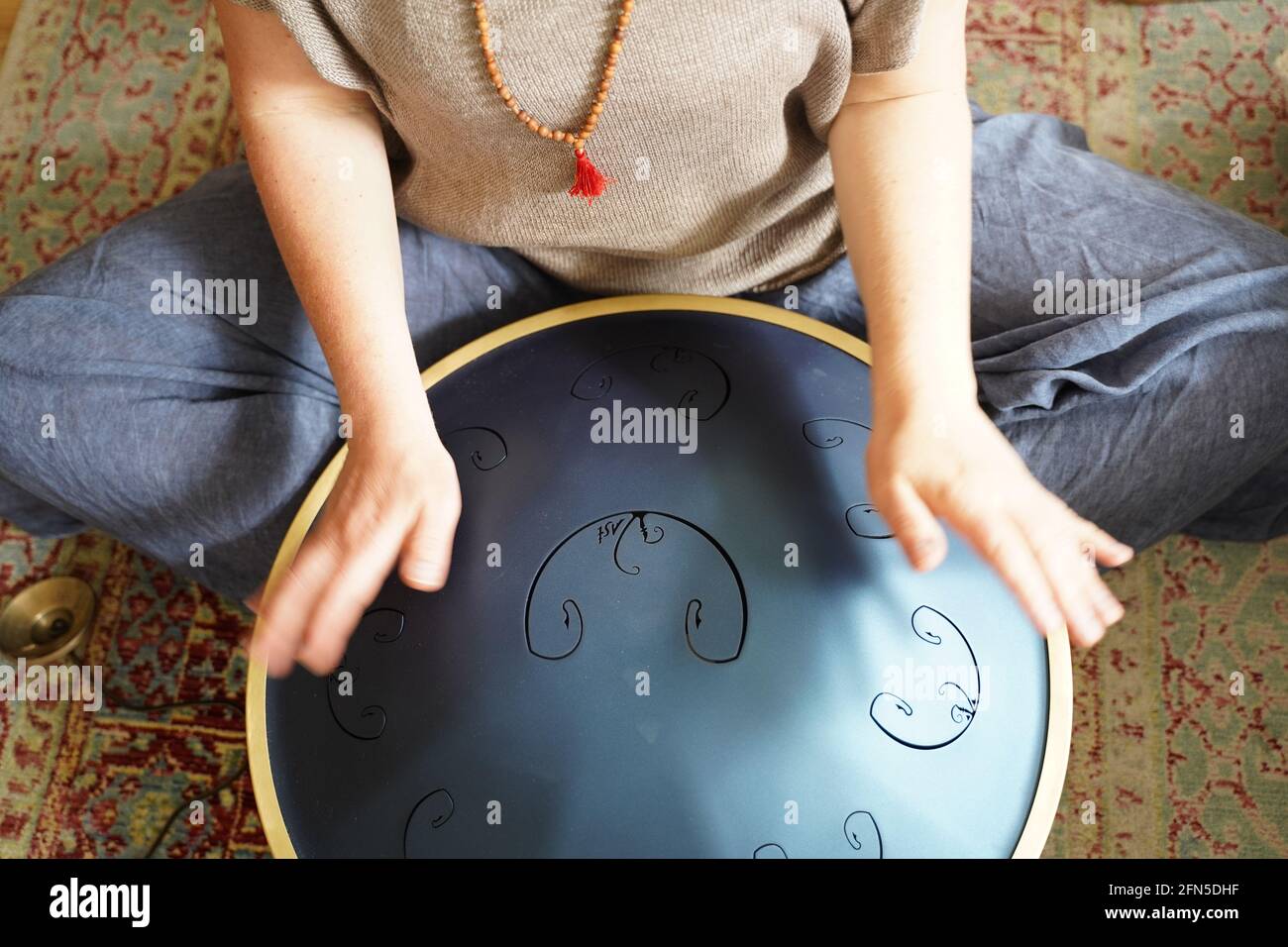 Woman with is playing a RAV Drum, close up of womans hands playing hang drum, music instrument for sound healing.Woman is playing a RAV Drum Stock Photo