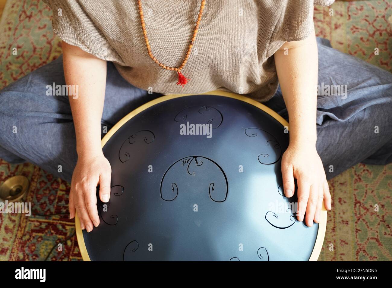 Woman with is playing a RAV Drum, close up of womans hands playing hang drum, music instrument for sound healing.Woman is playing a RAV Drum Stock Photo