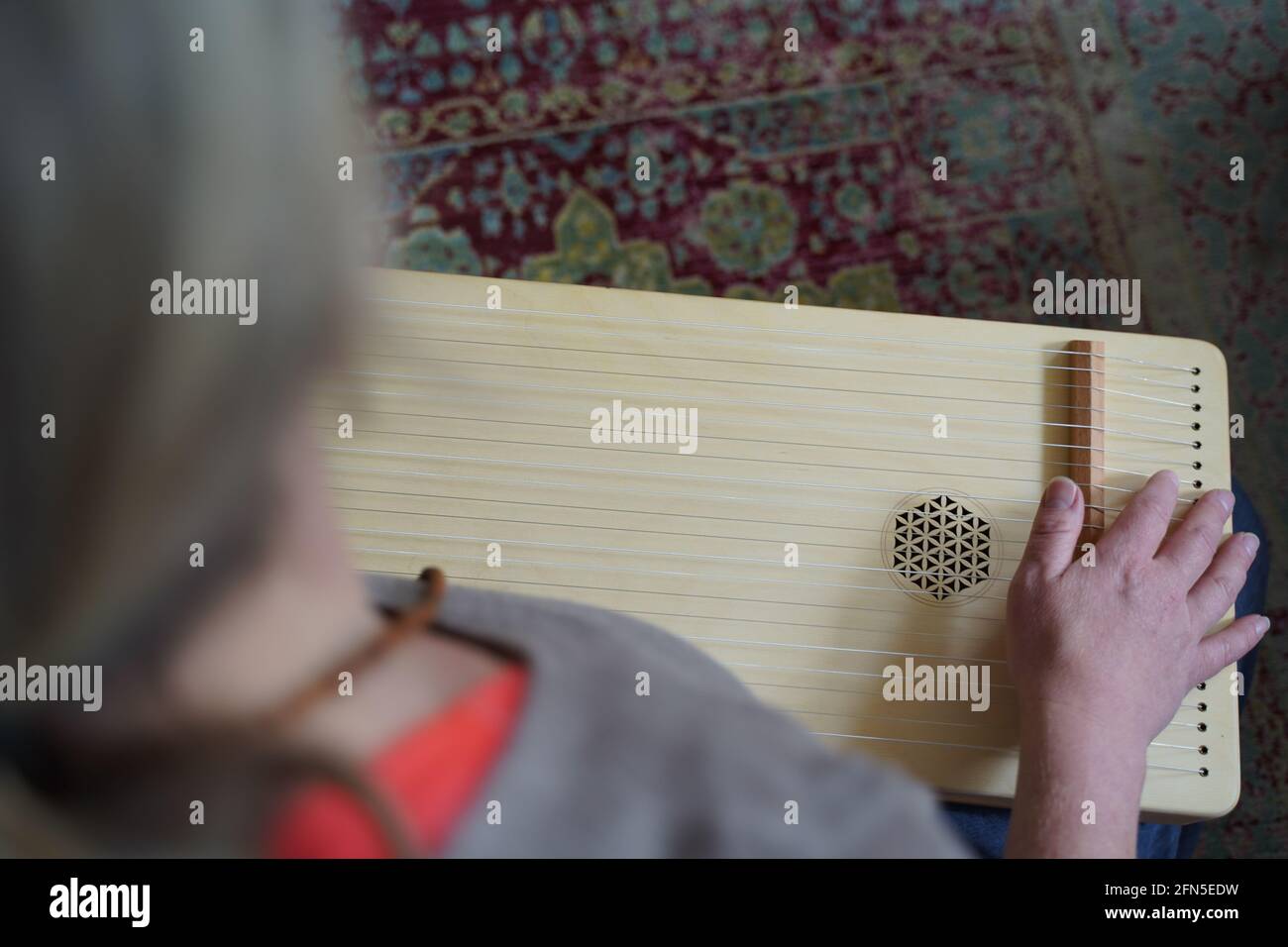 Woman holding a monochord, sound healing instrument in a therapy session. Stock Photo