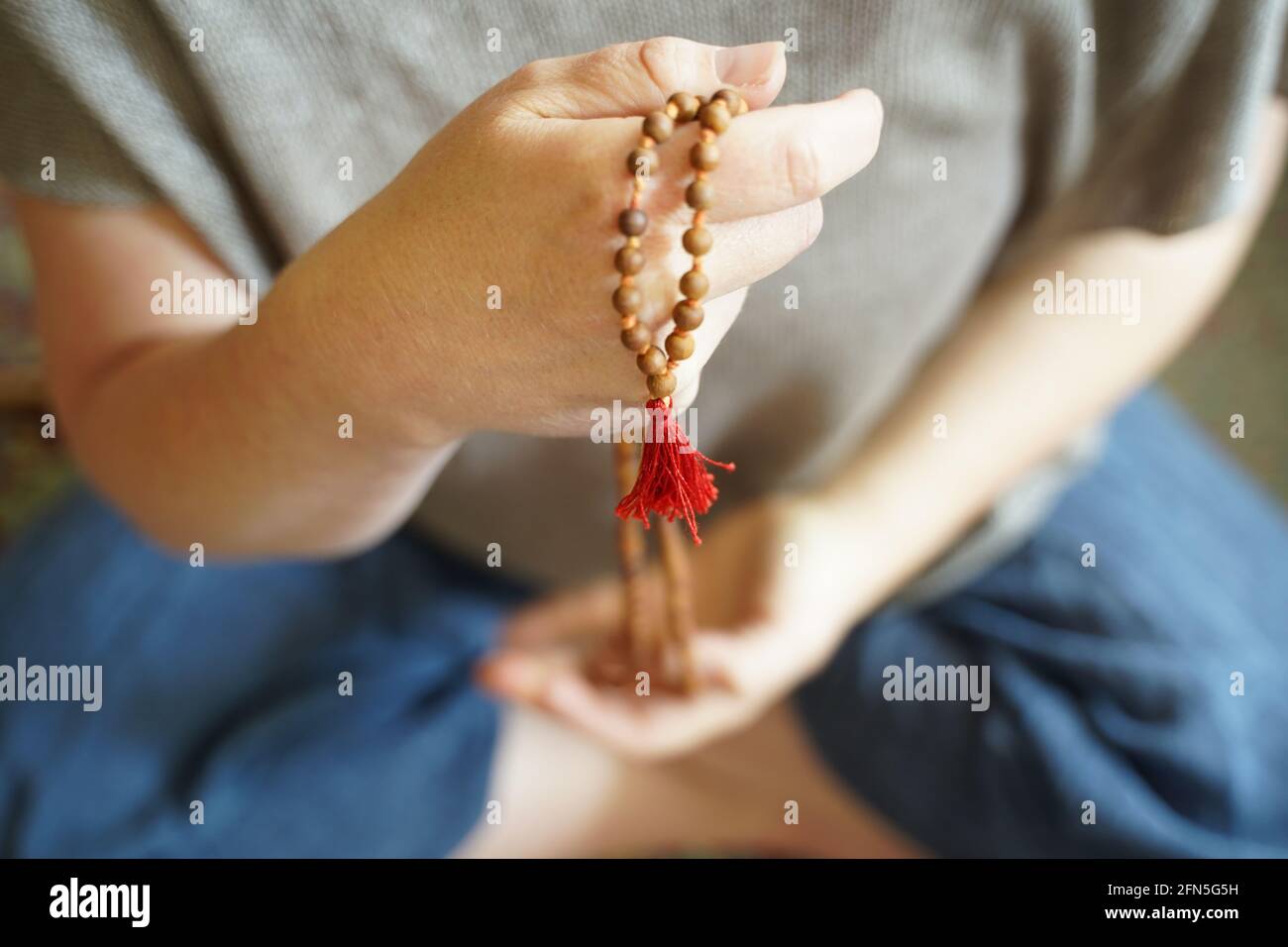 A  woman holding a mala yoga prayer bead necklace in her hand. Stock Photo