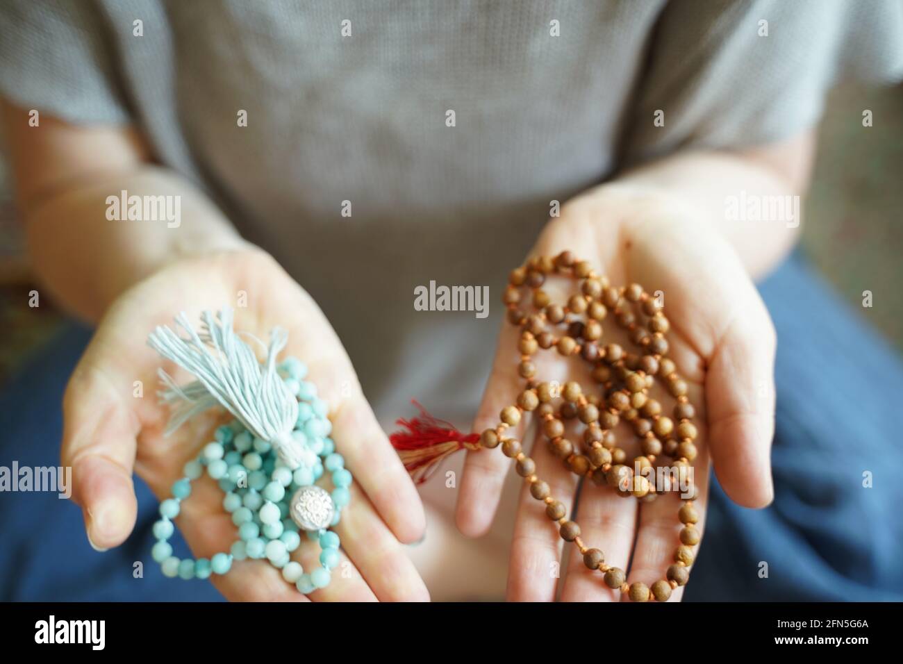 A  woman holding a mala yoga prayer bead necklace in each hand. Stock Photo