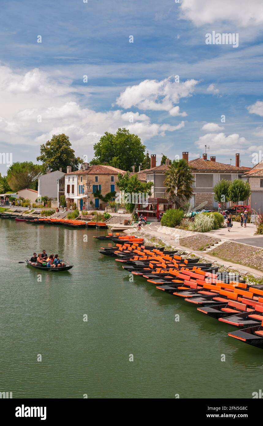 Orange tourist pleasure boats on the Sevre Niortaise river in the picturesque town of Coulon, Deux-Sevres (79) in the Marais Poitevin, the largest mar Stock Photo