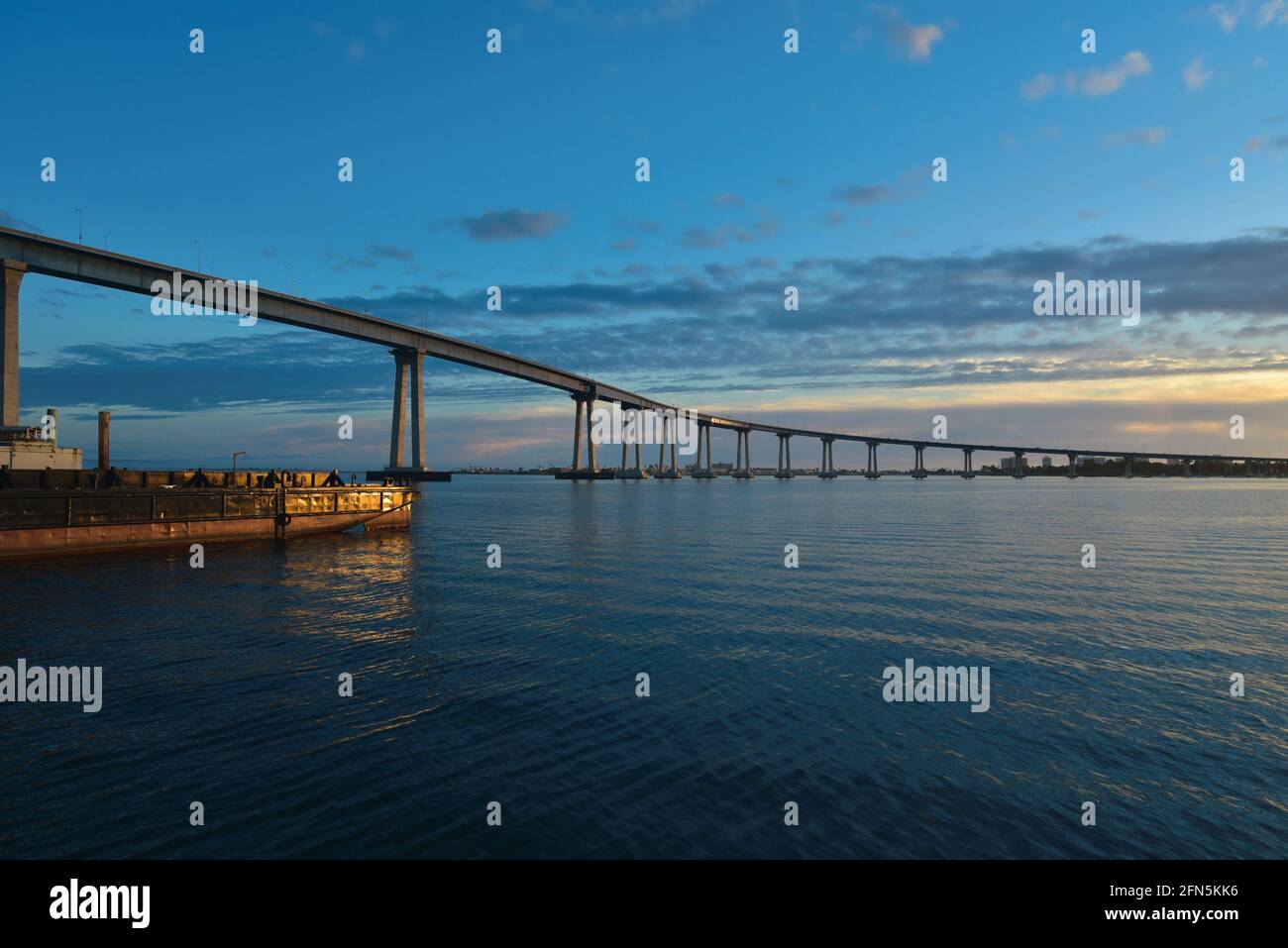 Sunset seascape with panoramic view of Coronado Bridge and a utility crew boat as seen from Cesar Chavez Park in San Diego, California. Stock Photo