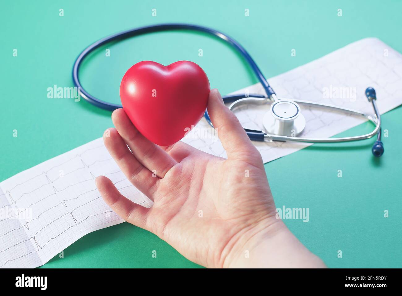 Doctor's hand with stethoscope heart and cardiogram on green background ...