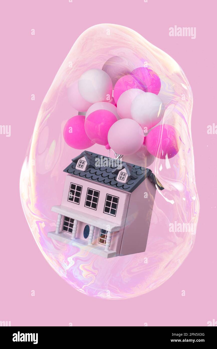 Creative idea with a house with a lot of colorful balloons in a soap bubble flying in the air. Minimal concept for advertising, marketing or artwork d Stock Photo