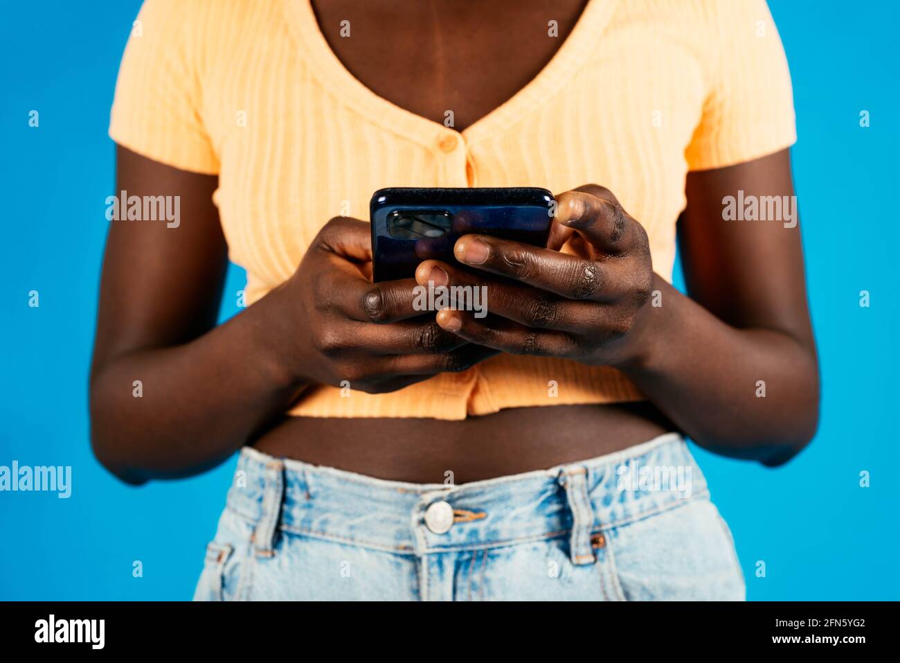 Crop woman using smartphone on blue background Stock Photo