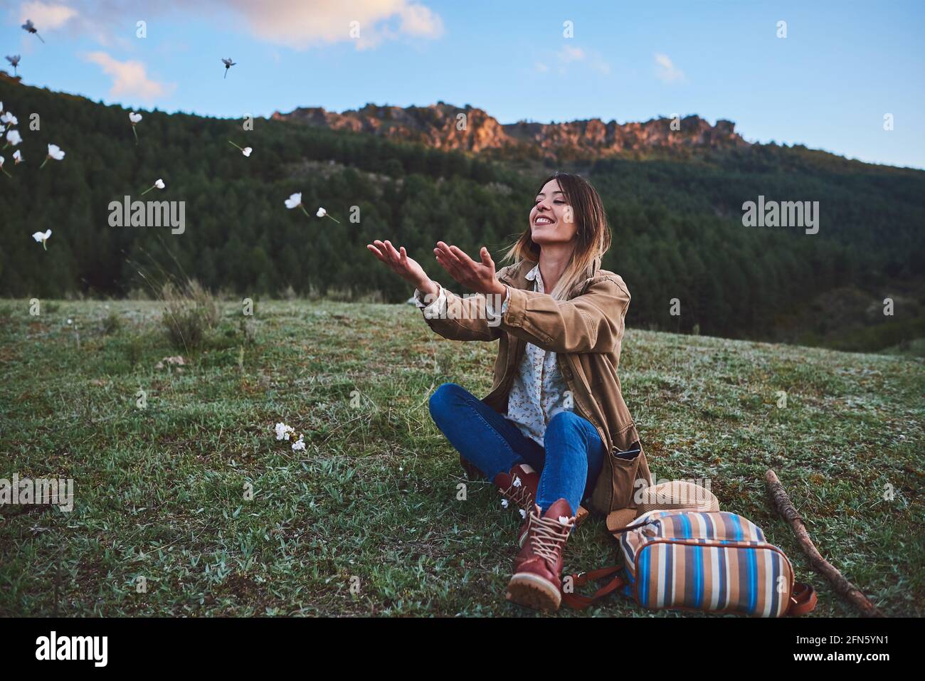 A happy woman in the mountains.She throws some flowers. Stock Photo