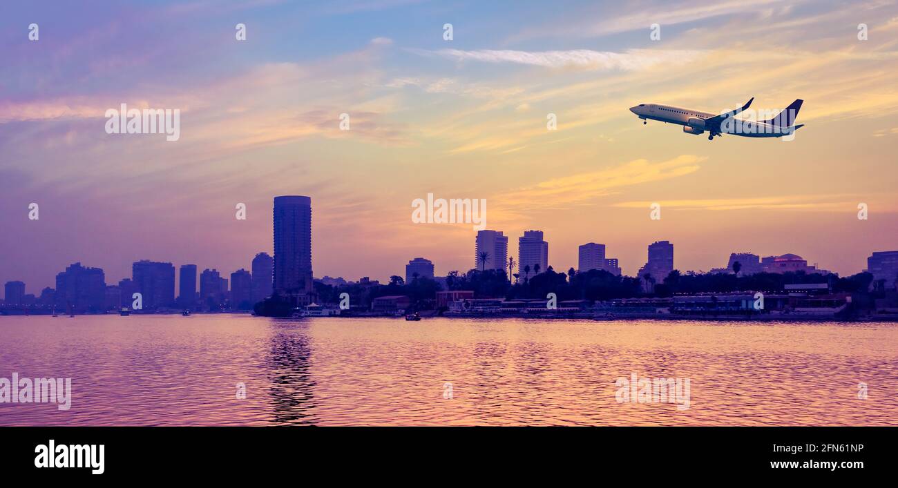 Passenger aircraft at cloudy sky over the Nile river at sunset in Cairo, panoramic view. Stock Photo