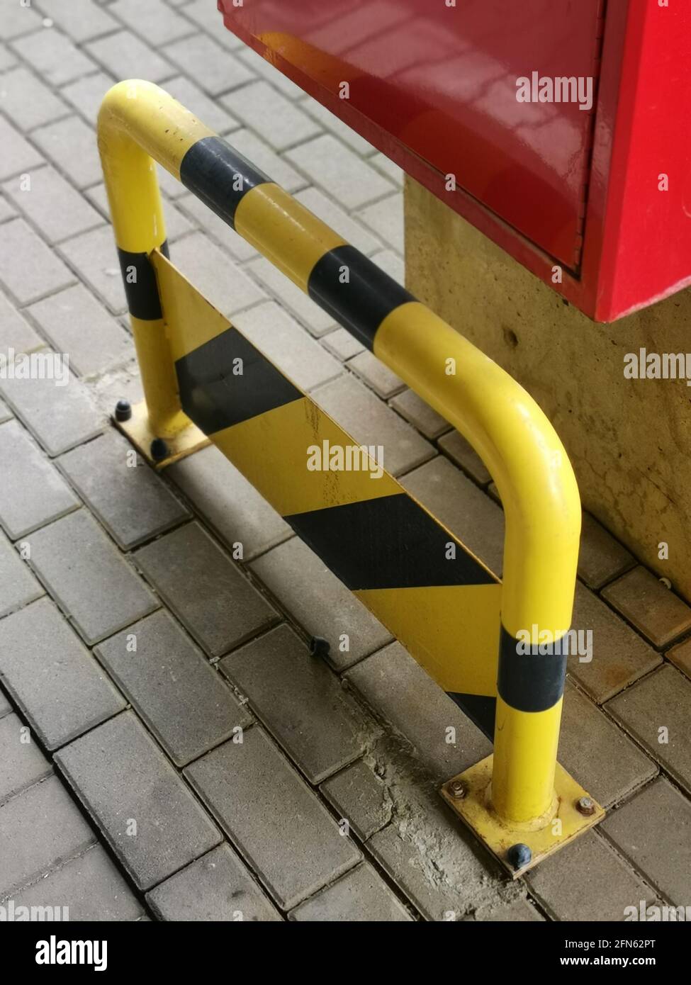 Yellow small safety rail with black stripes put outside by the wall ...