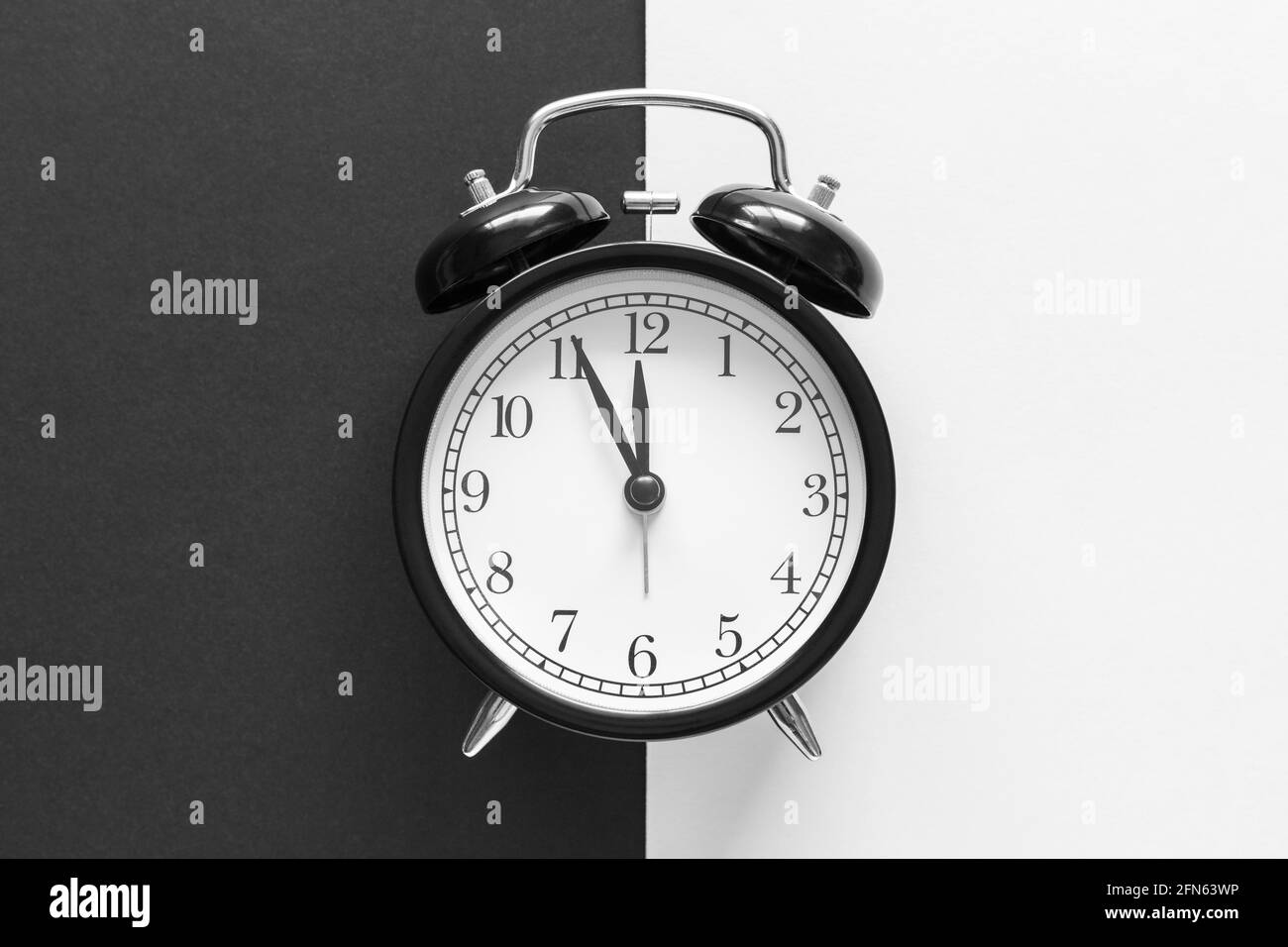 Classic alarm clock on black and white background. Time or day and night concept with copy space for text. Black and white image. Stock Photo