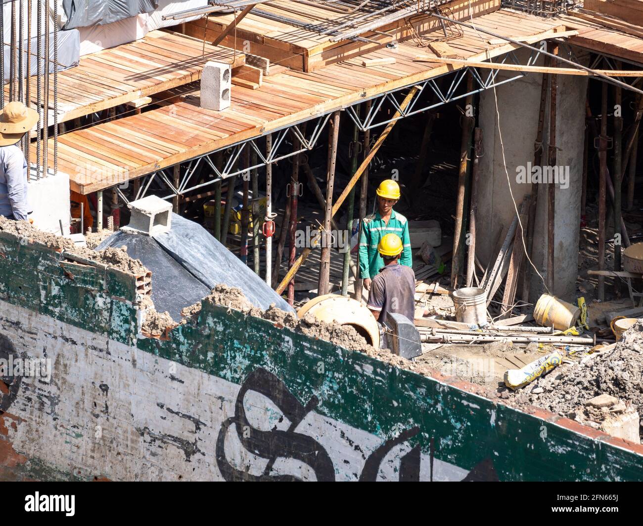 Medellin, Antioquia, Colombia - December 23 2020: Brown Men with Yellow Helmets Resting Among the Residues of a Building Construction Site Stock Photo