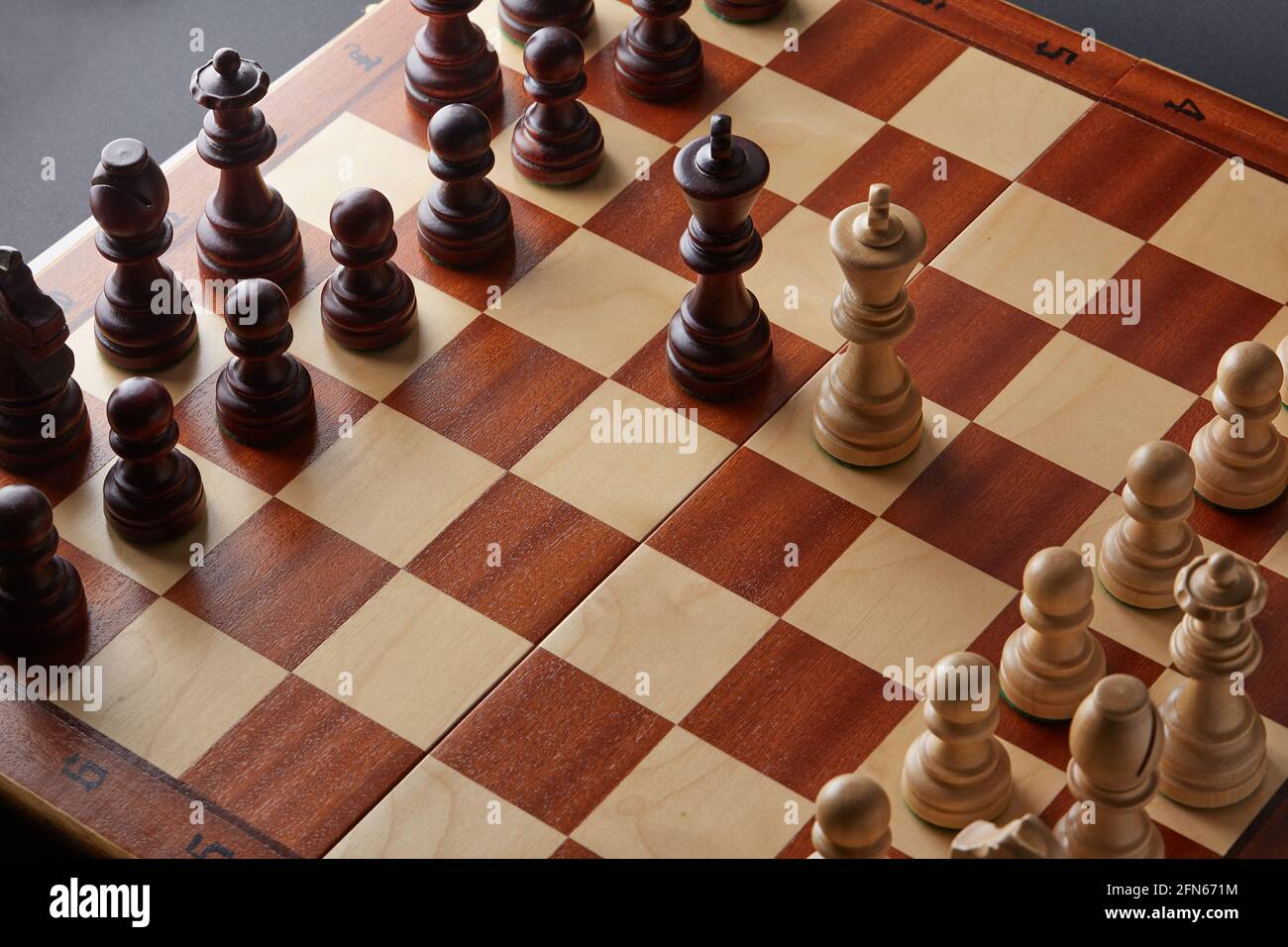 Classic Wooden Tournament chess set on black background. Two kings in centre of board other pieces lined up Stock Photo