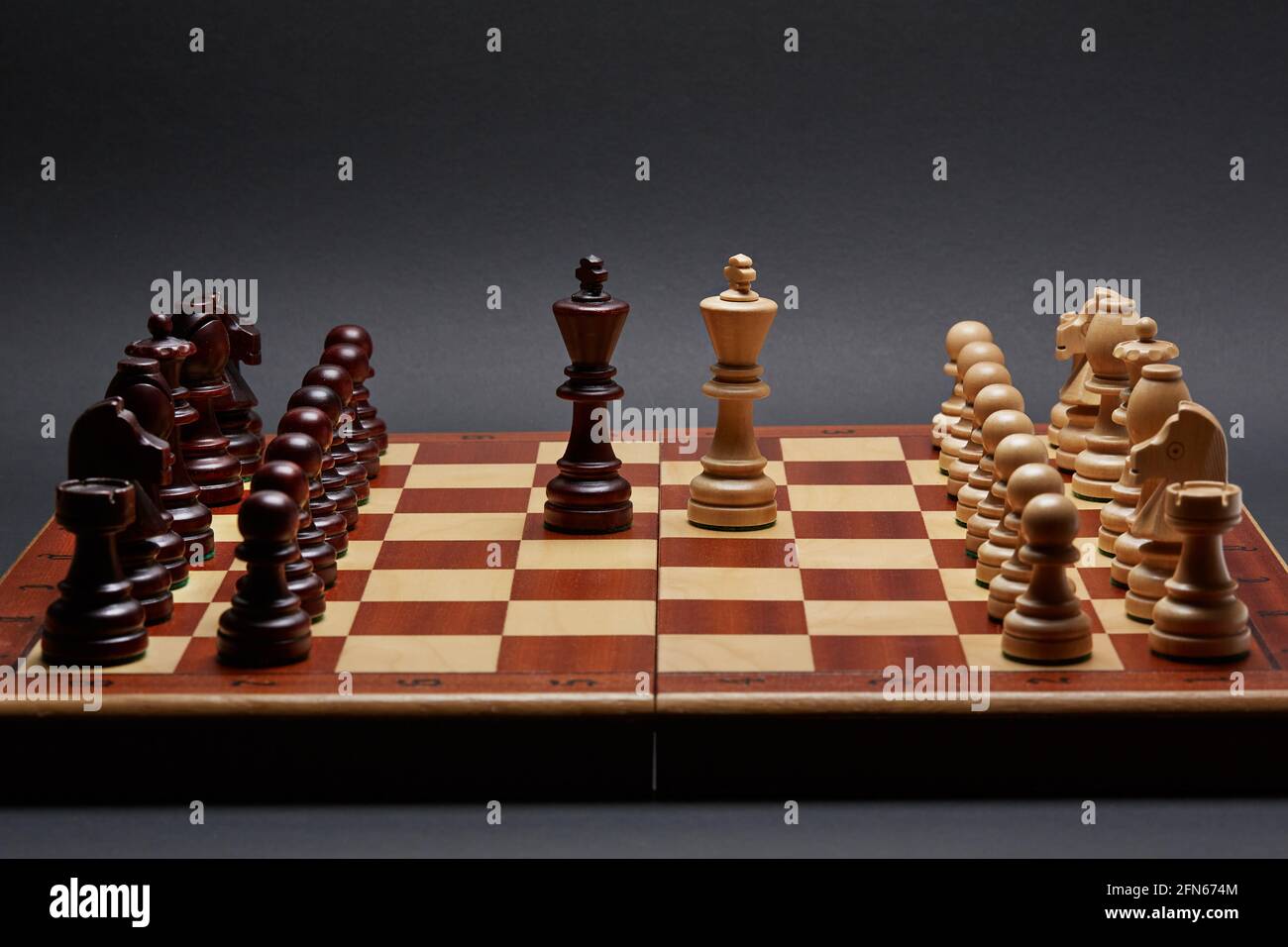 Classic Wooden Tournament chess set on black background. Two kings in centre of board other pieces lined up Stock Photo