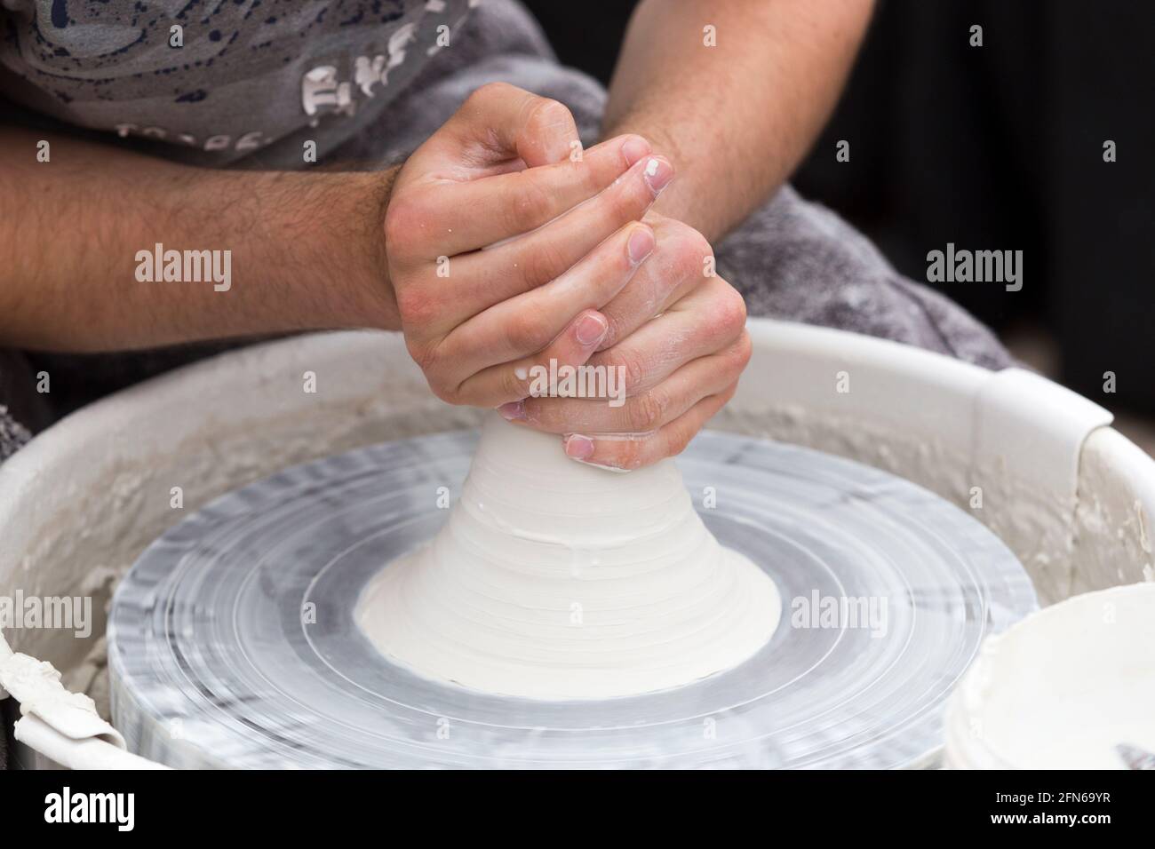 Potters hands skilfully rising / raising / lifting the centered clay before hand throwing a ceramic thrown hand made vase pot on a turning wheel. England. UK (123) Stock Photo