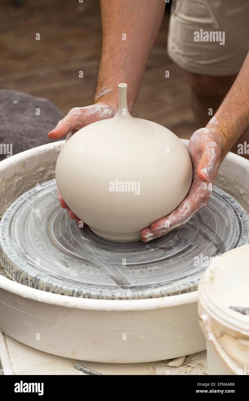Potters hands skilfully hand throwing a ceramic thrown clay vase pot on a turning wheel. England. UK (123) Stock Photo