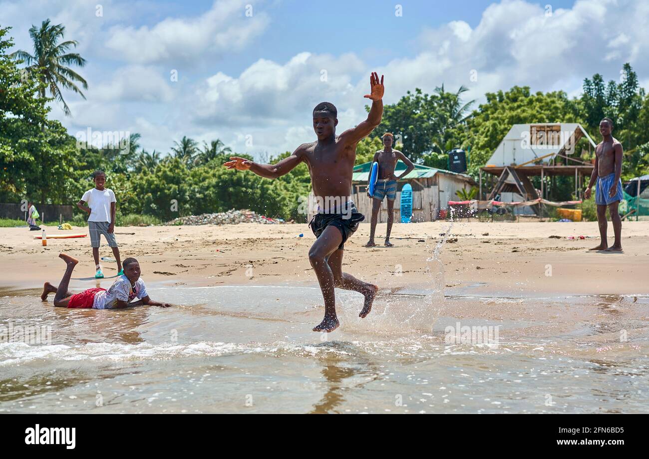 African American teen playing with the waves of the ocean on a clear ...