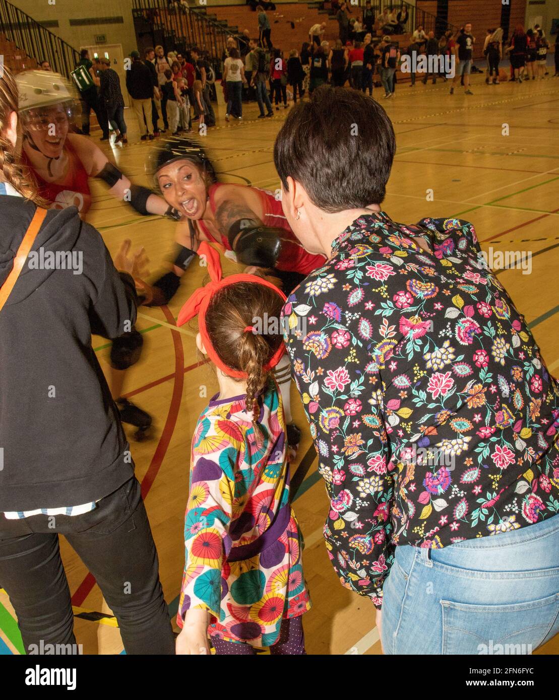 At the end of a bout a delighted Rebellion Roller Derby skater high fives spectating friends Stock Photo