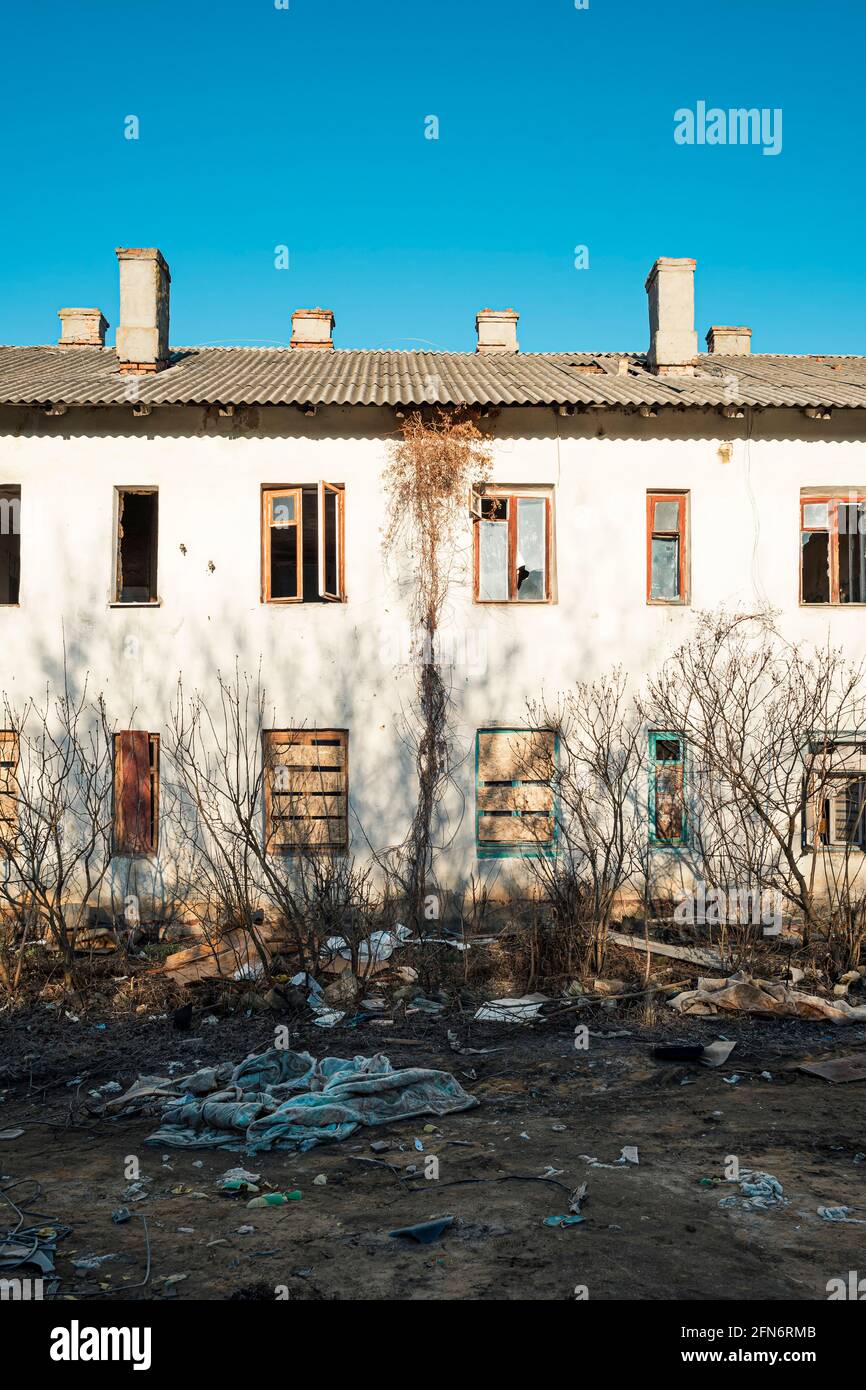 The facade of an abandoned two-story house with broken glass and ...