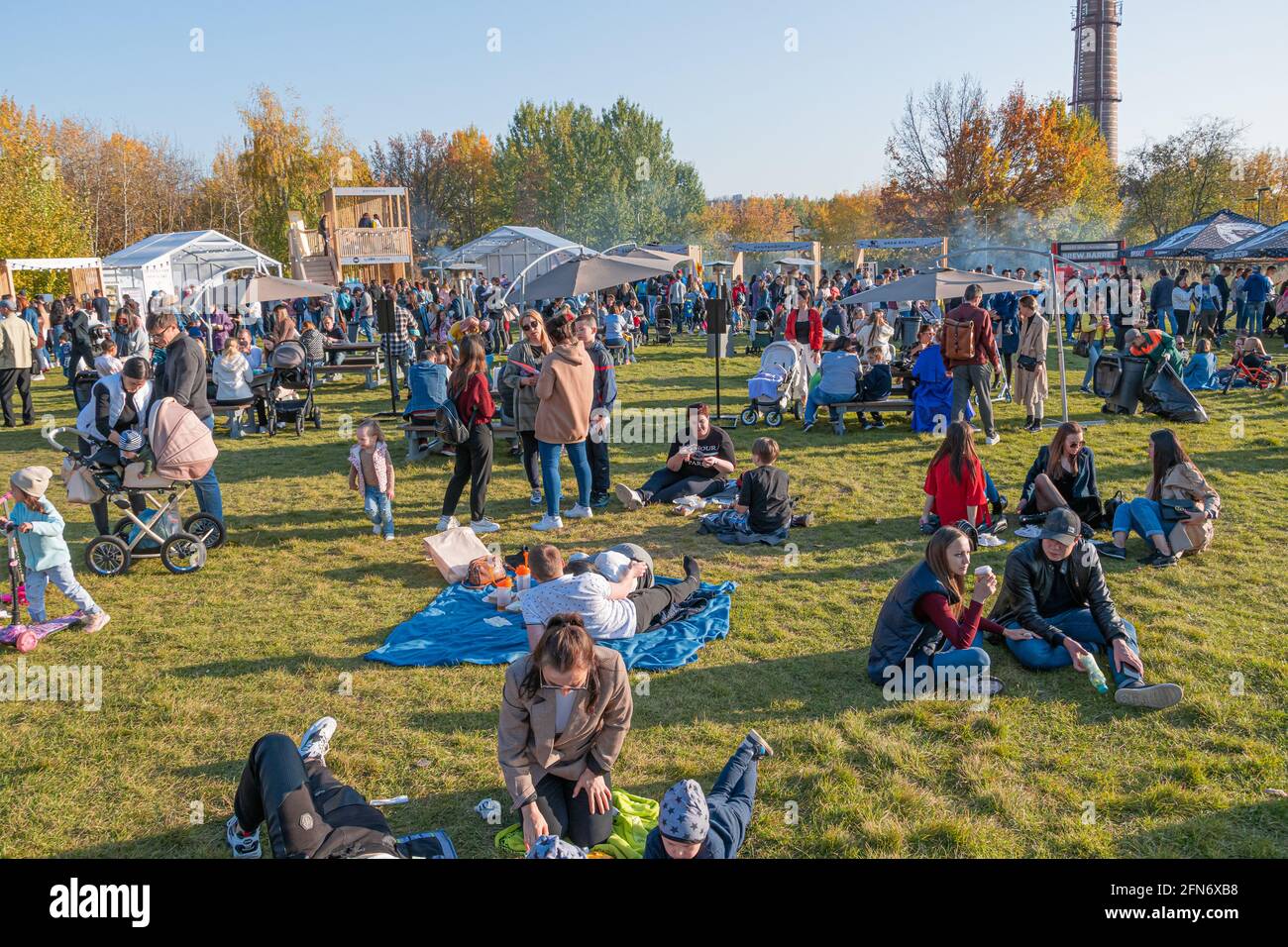 Kazan, Russia - October 03, 2020: Residents relax, sit and lie on the lawn in the city park, around which there are many mobile barbecue restaurants. Stock Photo